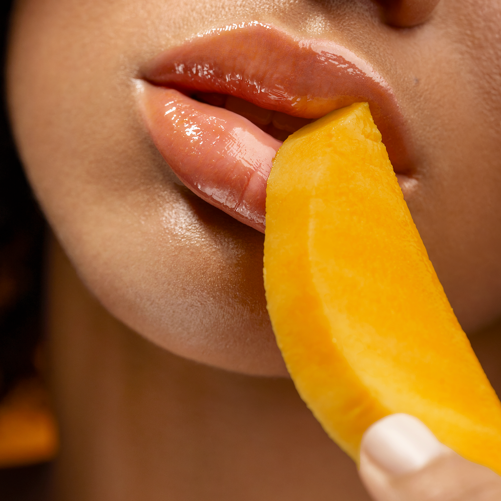 Close-up of a person biting into a yellow fruit slice.