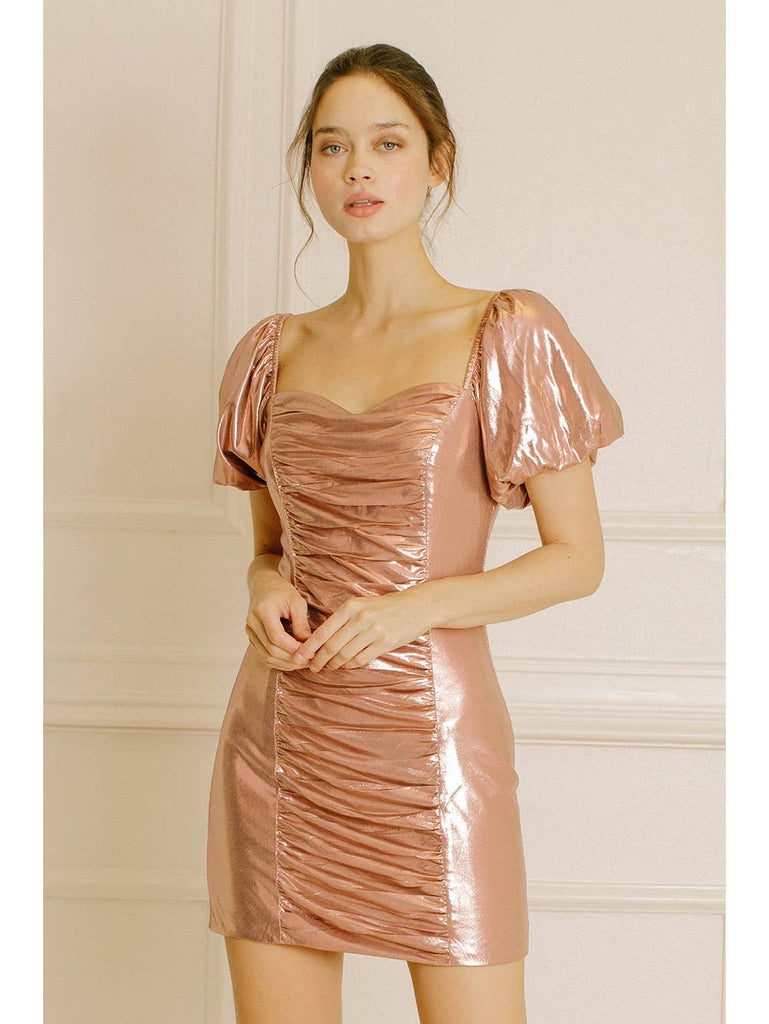 Monochromatic foil metallic mini dress. It exhibits a sweetheart neckline, short puffy sleeves, and a fitted bodycon silhouette. It also has a back invisible zipper, a ruched front/center and a back/center.