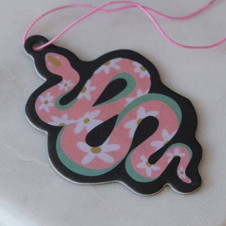 Decorative snake-shaped tag with floral patterns on a marble surface