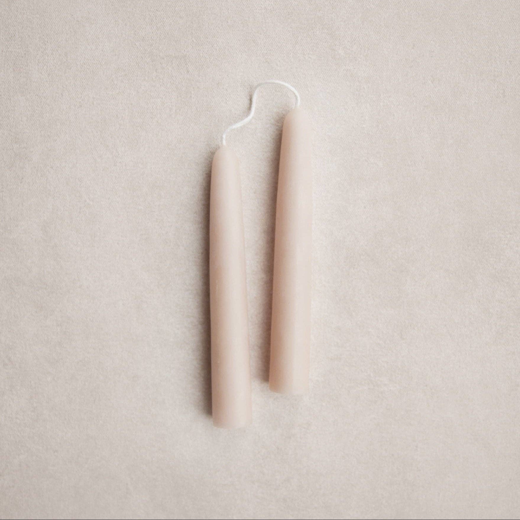 Two slim, tapered salt-colored candles