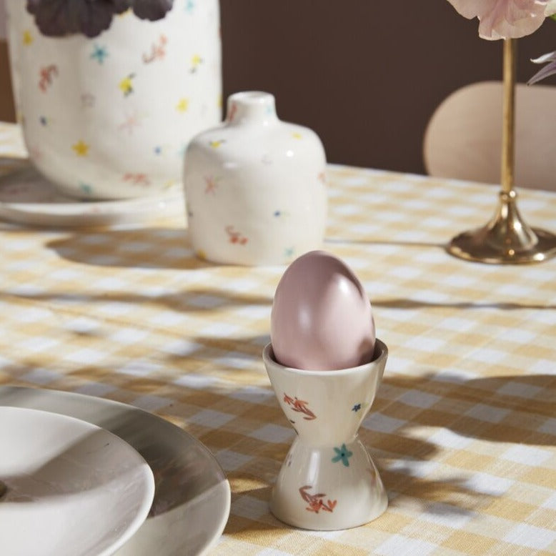 Introducing the Ditsy Eggs Cup, the perfect addition to your kitchenware collection. This quirky and fun cup is perfect for holding your eggs (and your attention). Add a dash of whimsy to your breakfast table with this must-have item!     Sizes  2"x 3"