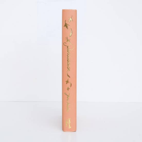 Peach-colored book with gold text and design on a white background