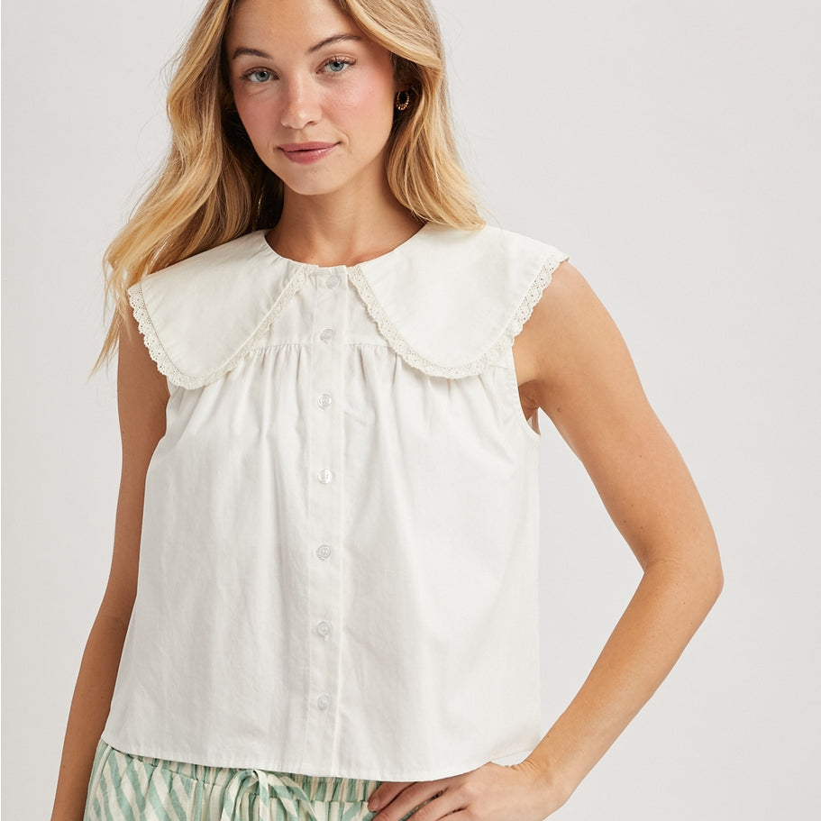 White sleeveless blouse with buttons and a large lace edged pan collar. 