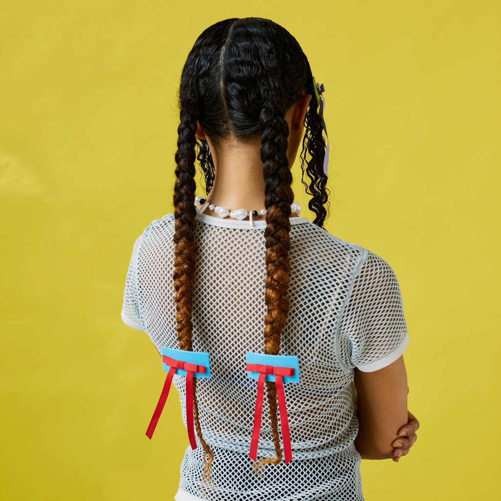 She’s giving Sailor Moon sweetness in this bow barrette in blue/red. This French barrette-style clip works for most hair types.  Measures  3" x 5" (includes ribbon tail)