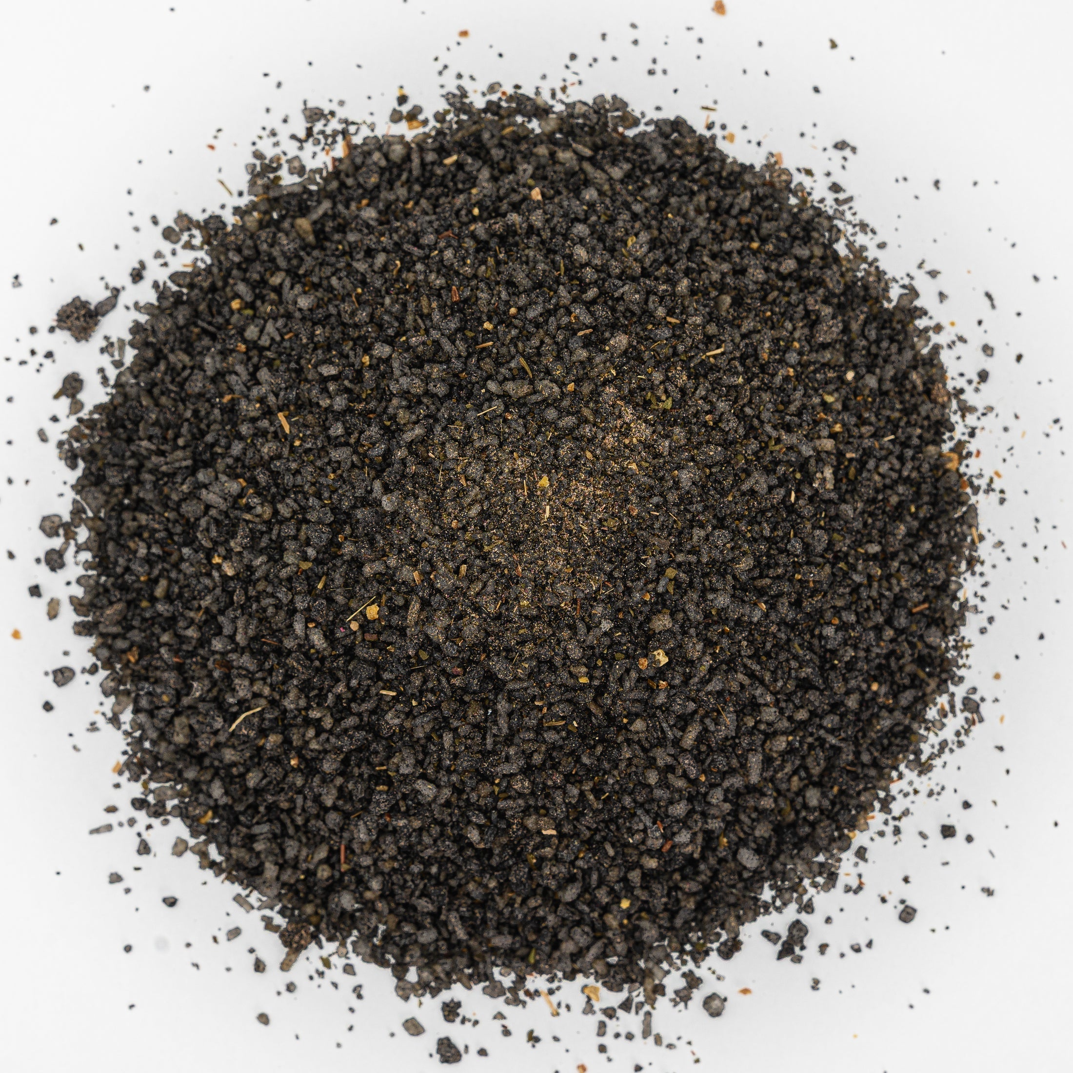 Mound of black salt with flecks of herbs. 