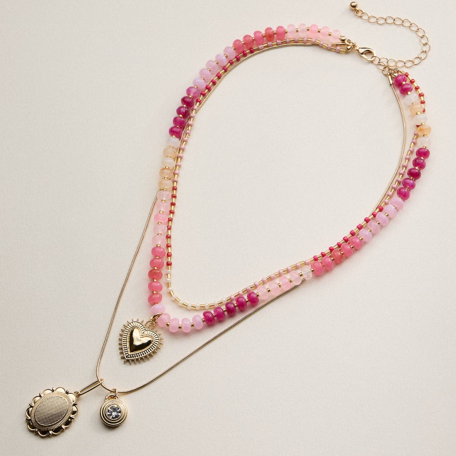 This layered necklace set combines texture and shine for an effortlessly chic look. Designed with strands of glass beads, gold cube accents, and delicate snake chains, it features a mix of heart and round pendants for a modern romantic finish. The adjustable chain and secure lobster clasp ensure a comfortable fit, perfect for everyday wear or special occasions.

Details:

Material: Glass beads with gold-tone metal chains and pendants
Design: Three-layer necklace with beaded strands and charm pendants