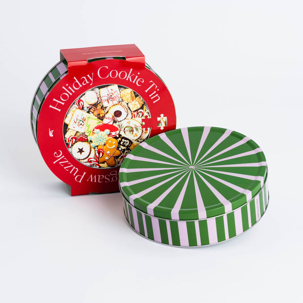 Holiday kitsch has reached new heights: our cookie tin jigsaw puzzle is chock-full of holiday cheer. This round puzzle comes in a collectible candy-striped tin — a gift that keeps on giving.     Product Info  750 piece puzzle Completed puzzle is 22 inches across  Collectible candy-striped tin  Packaging is 10.25 x 10.25 x 2.7 inches 