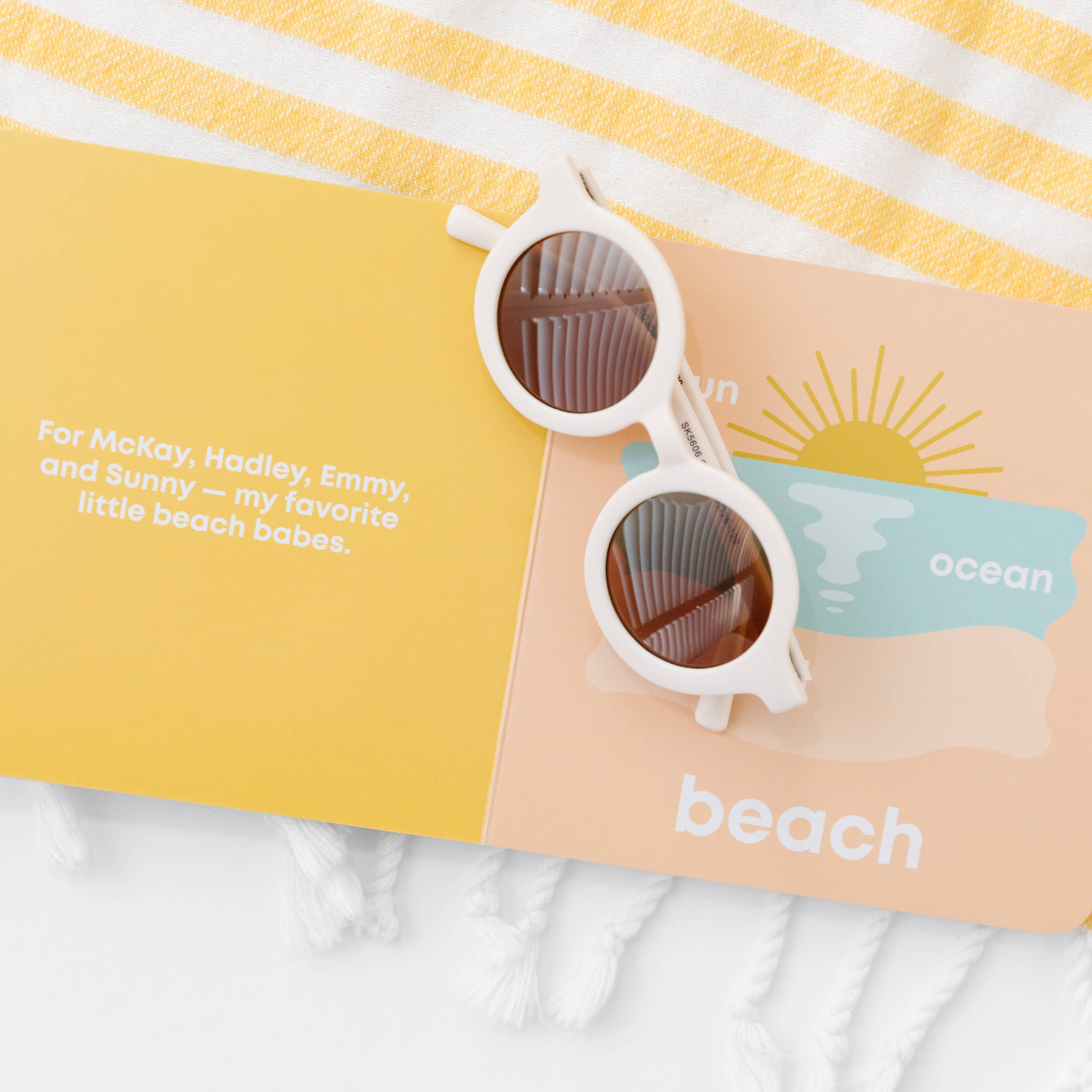 Sunglasses on a personalized beach towel with text and branding.