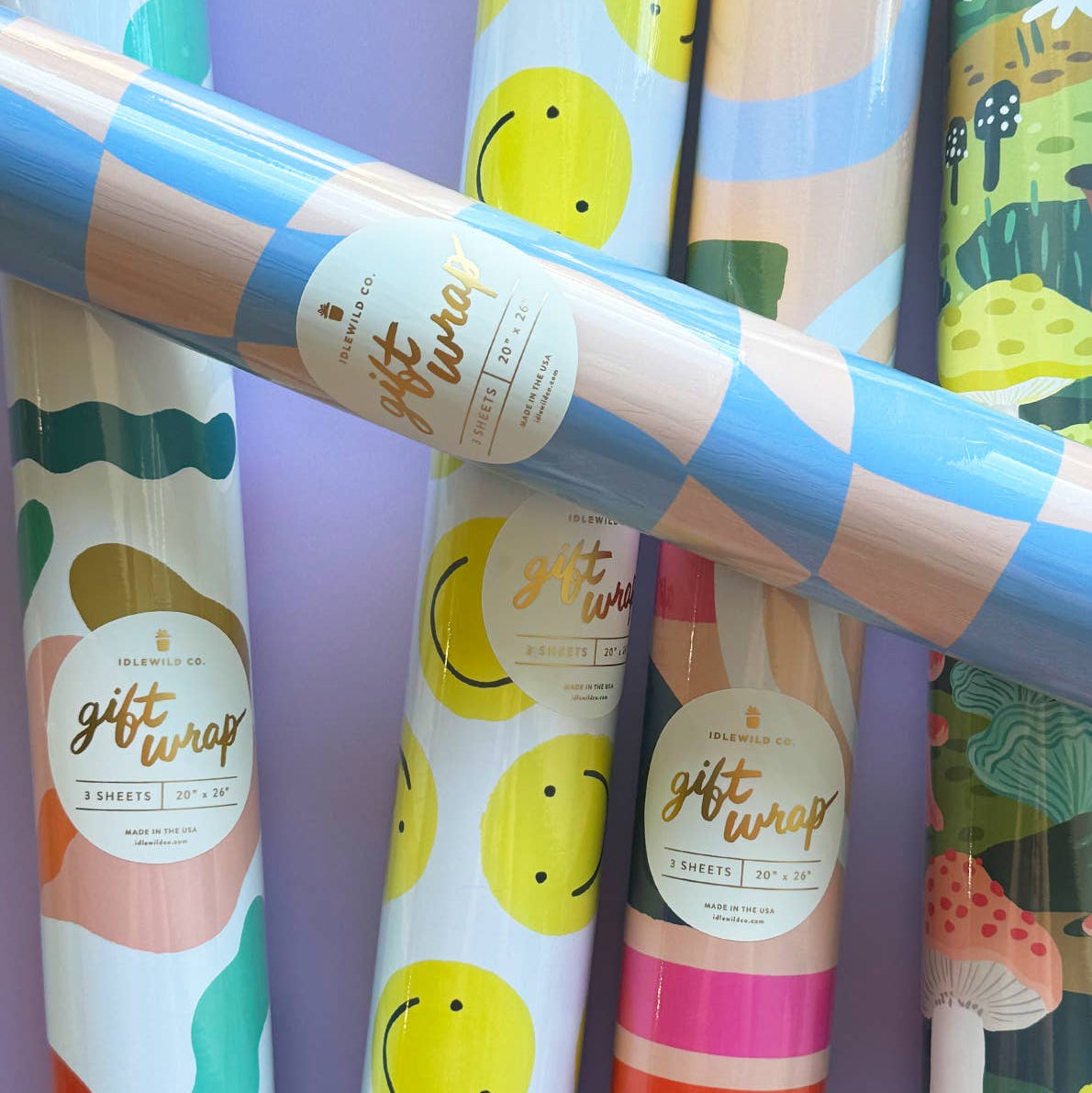 Rolls of colorful gift wrap paper with various designs on a purple background.