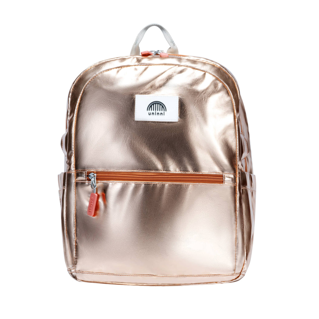 Introducing the Ethan Backpack in Metallic Gold. Perfect for standing out in a crowd, this backpack is made with a shimmering gold fabric that is sure to catch everyone's attention. With spacious compartments and adjustable straps, it's both practical and stylish.