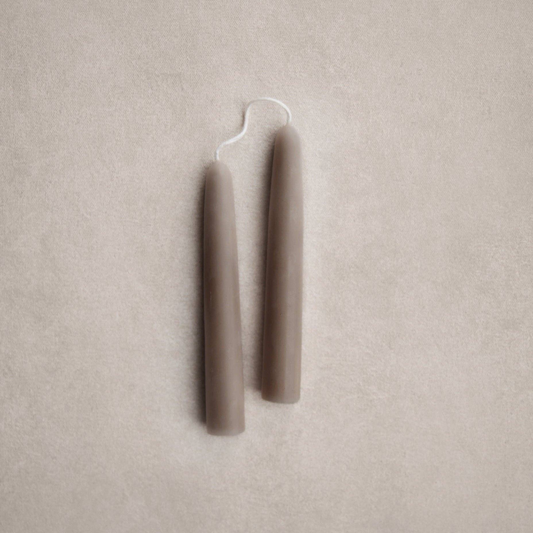 Two beige candles on a beige background. Thyme