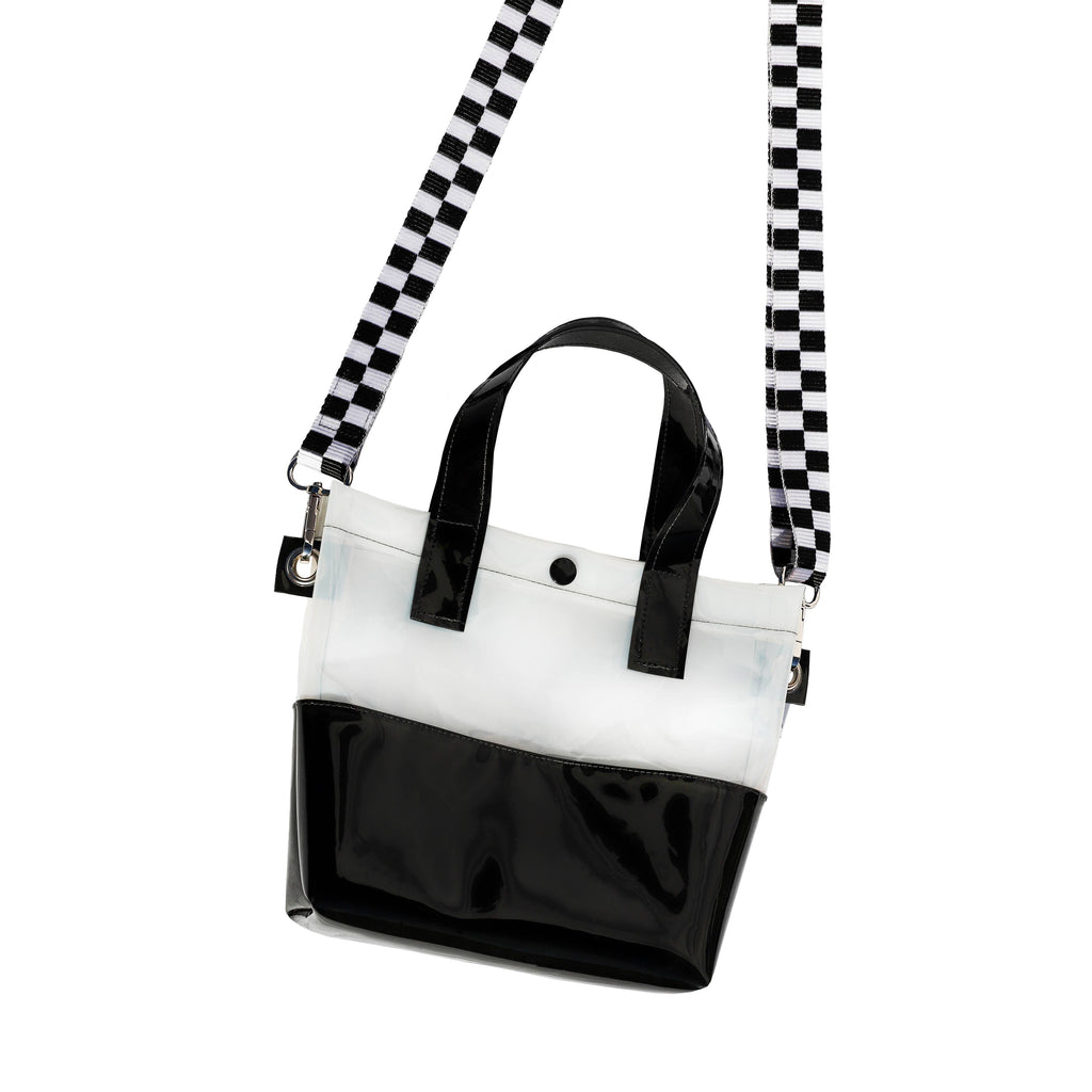 Miss your jelly sandals? This is your new favorite bag! Keep everything inside with a snap. The black and white translucent vinyl handle bag has a black snap closure and is detailed with silver metal grommets. It's available with or without the detachable black and white checkered 1" strap