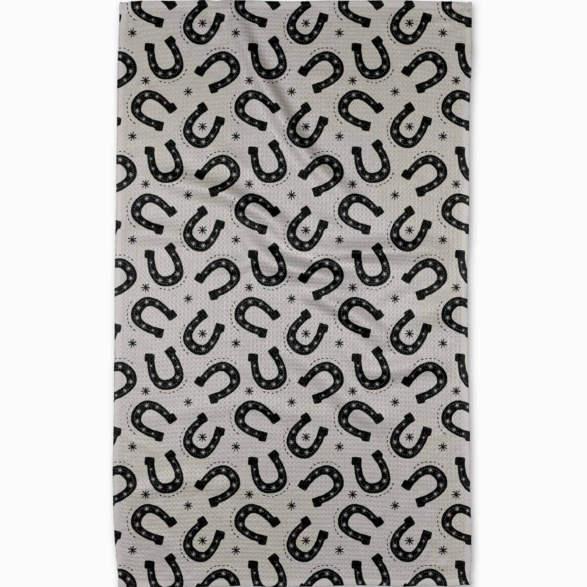 Tea towel with black horse shoes pattern on a grey background