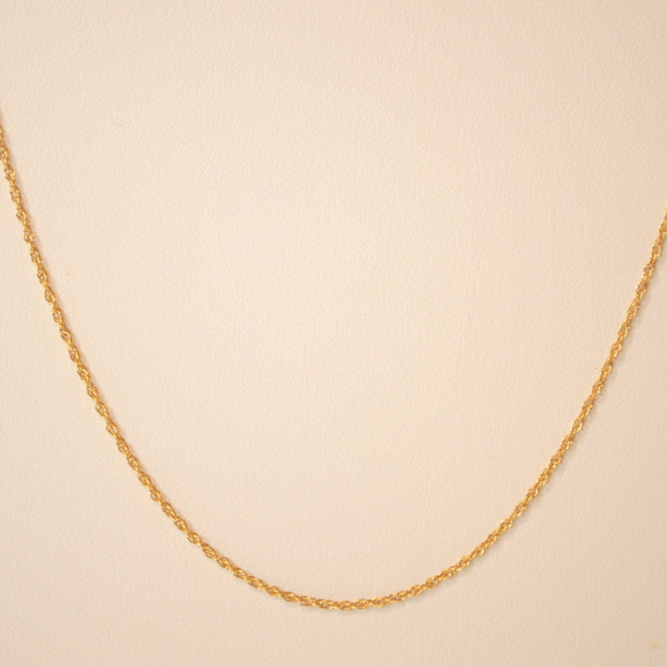 Gold chain against an off white back ground.