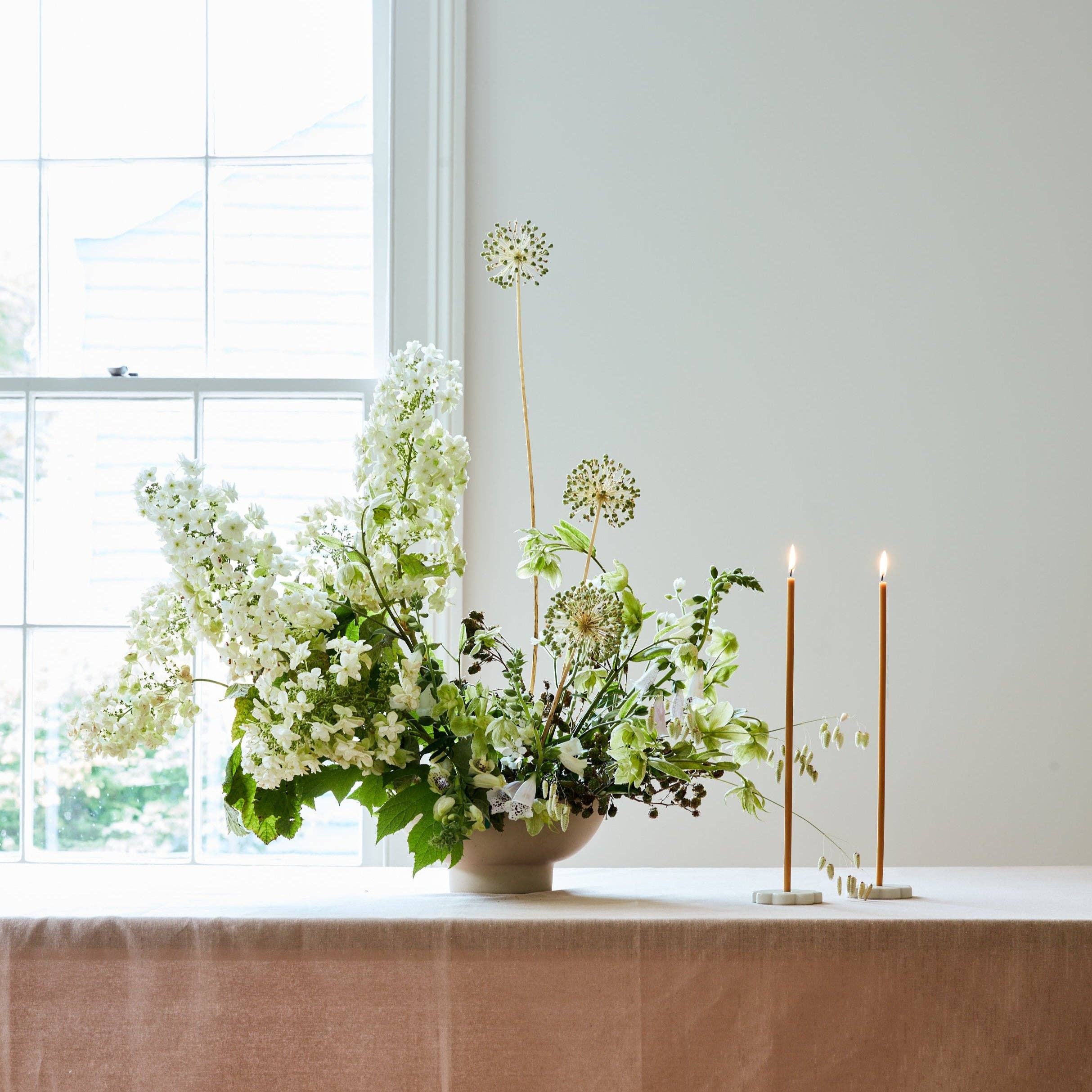 Floral arrangement in a vase with two candles on a windowsill