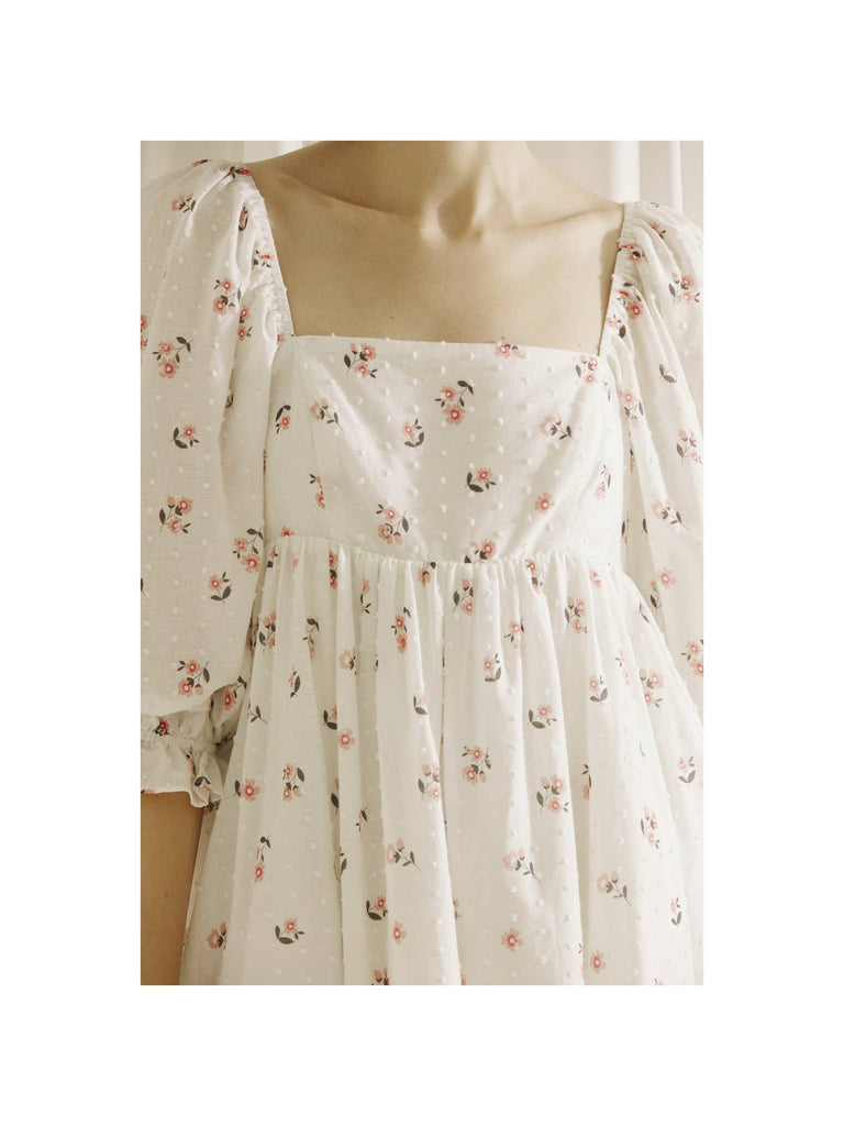 Embroidered little flowers and swiss dot baby doll mini dress. It displays a square neckline, 3/4 puffy sleeves, and two bust darts. It also has an empire gathered waist and a back zipper for off/on access.