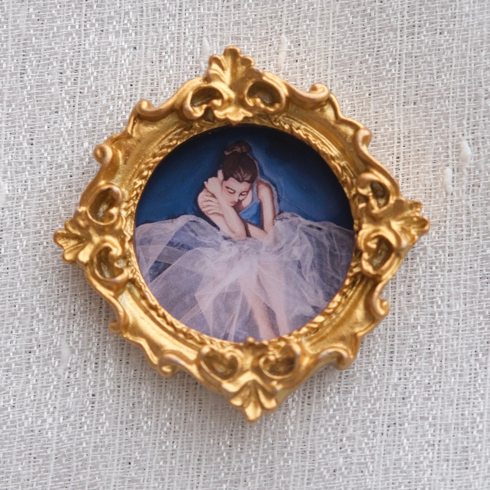 A solo ballerina pondering seriously. Set in a gold resin frame. 