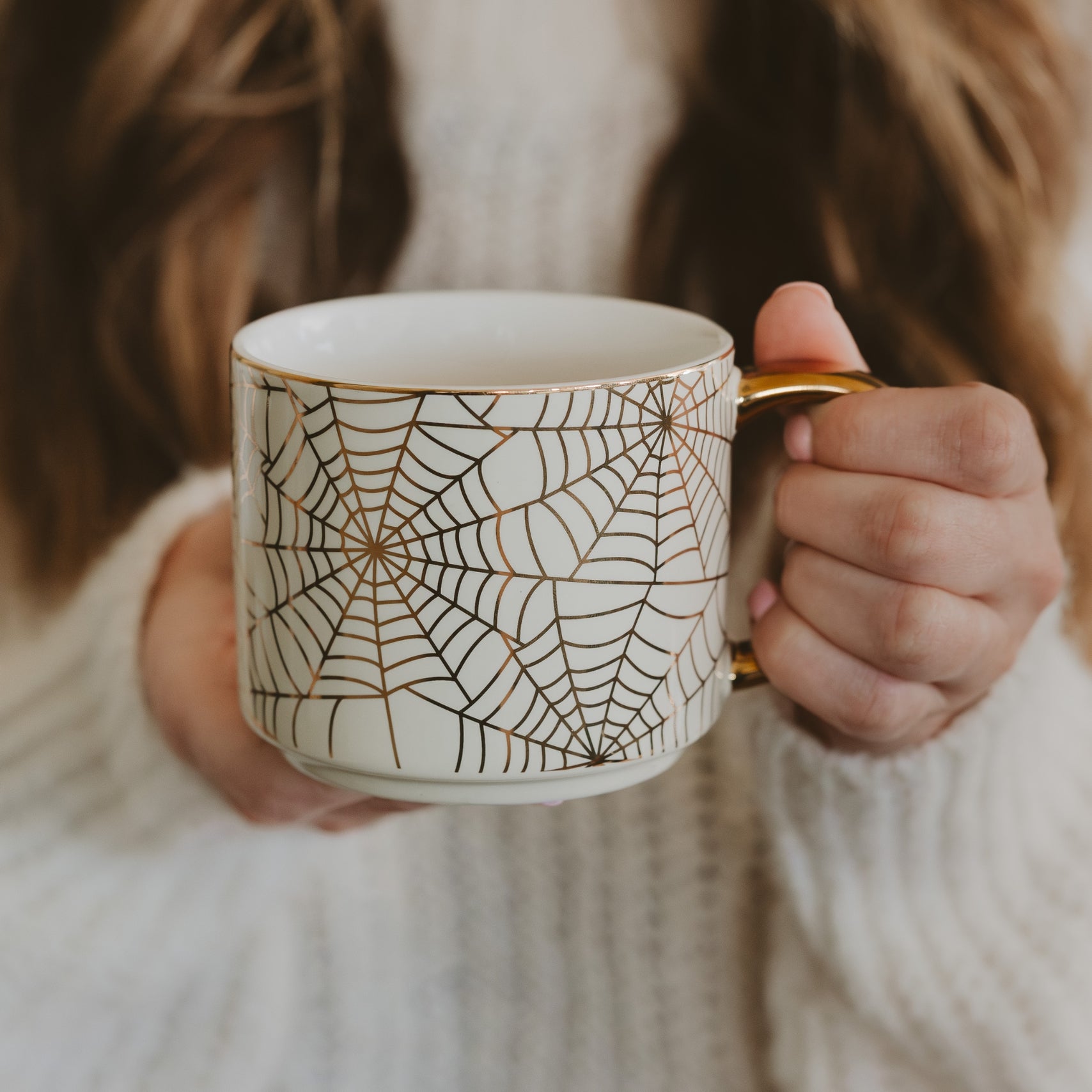 Person holding a mug with a spider web pattern