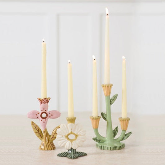 Decorative candle holders with candles on a white surface, displayed on a website page.