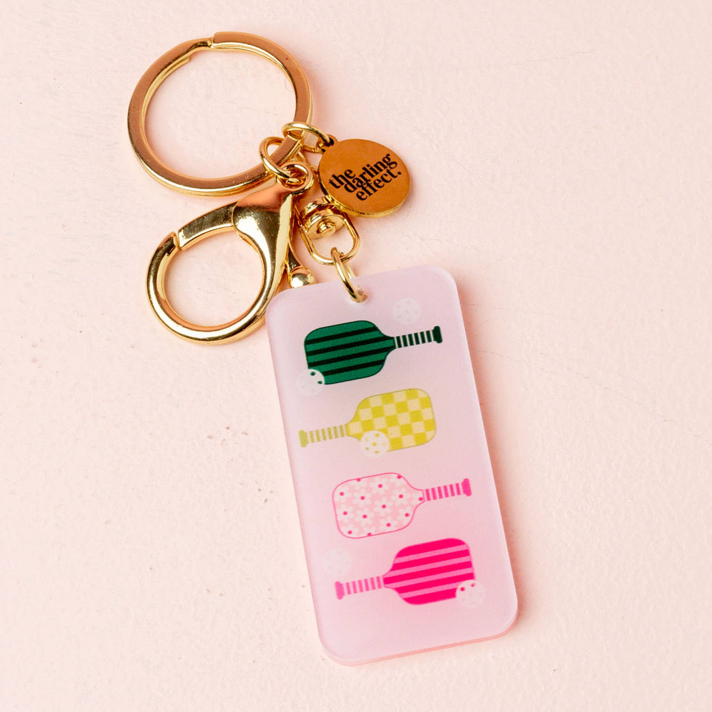 Express yourself with our Acrylic Keychains—mini statements of style and fun! Featuring colorful pickleball paddles, these keychains are perfect for adding a little flair to your keys, bags, or backpacks.

Crafted from lightweight, durable acrylic and finished with gold hardware and our signature logo charm, they’re as chic as they are functional. These keychains are the cutest pocket-sized accessory to showcase your unique vibe!