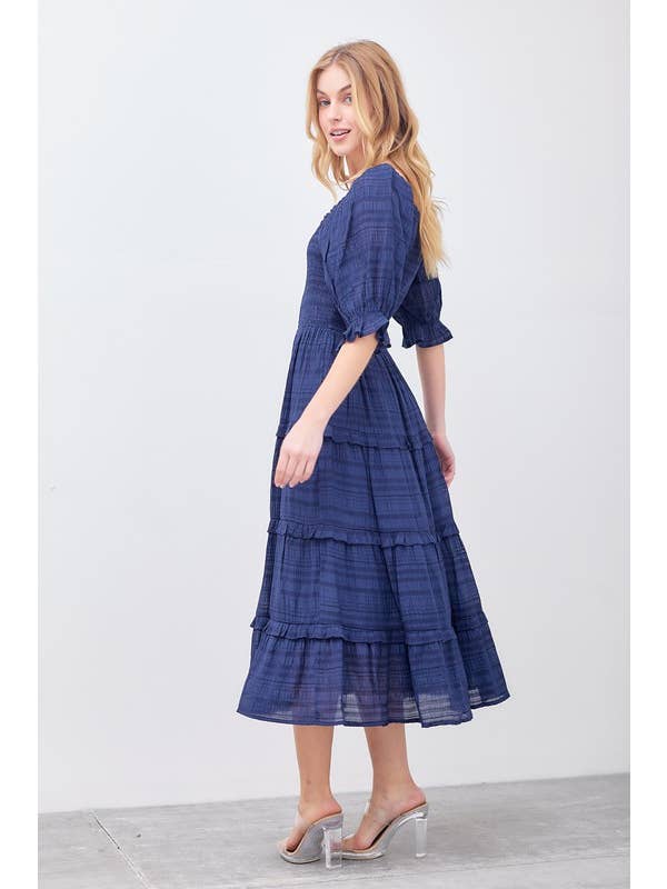Take your style up a notch with our Navy Tiered Midi Dress. This unique dress features playful layers and a delicate marrow hem detail. Perfect for a day out or a special event, this dress will surely turn heads and add a touch of whimsy to your wardrobe.
