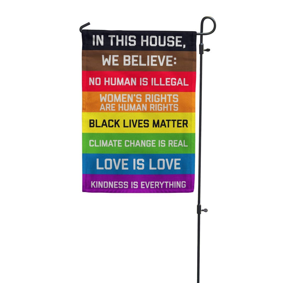 Garden flag with the following text on a rainbow field:

IN THIS HOUSE, WE BELIEVE: NO HUMAN IS ILLEGAL WOMEN'S RIGHTS ARE HUMAN RIGHTS BLACK LIVES MATTER CLIMATE CHANGE IS REAL LOVE IS LOVE KINDNESS IS EVERYTHING These garden flags are a thick double-sided construction and double-stitched all around. They have a pole pocket along the top to fit any standard garden flag stake (not included). 18" x 12"
