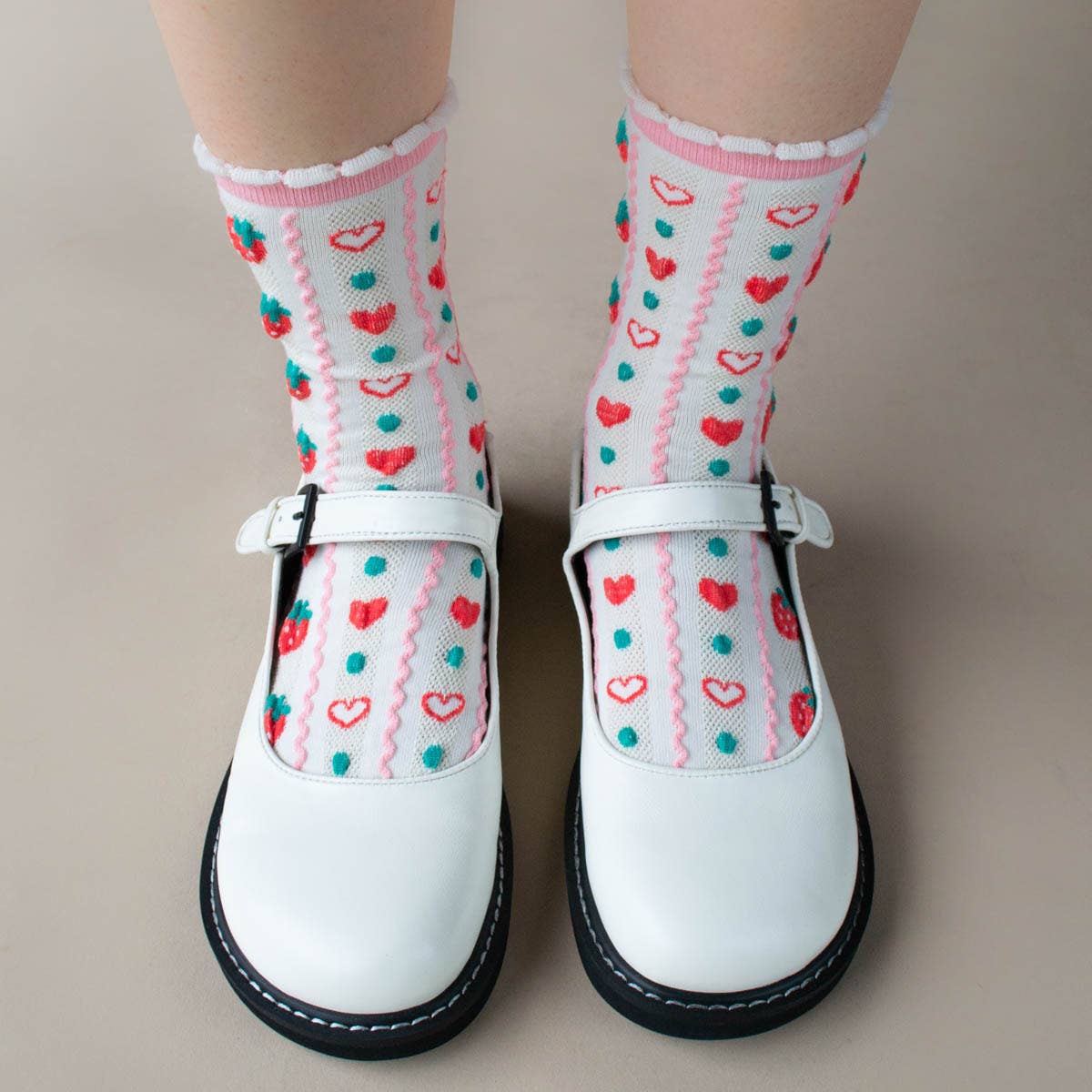 White shoes with colorful heart-patterned socks on a neutral background