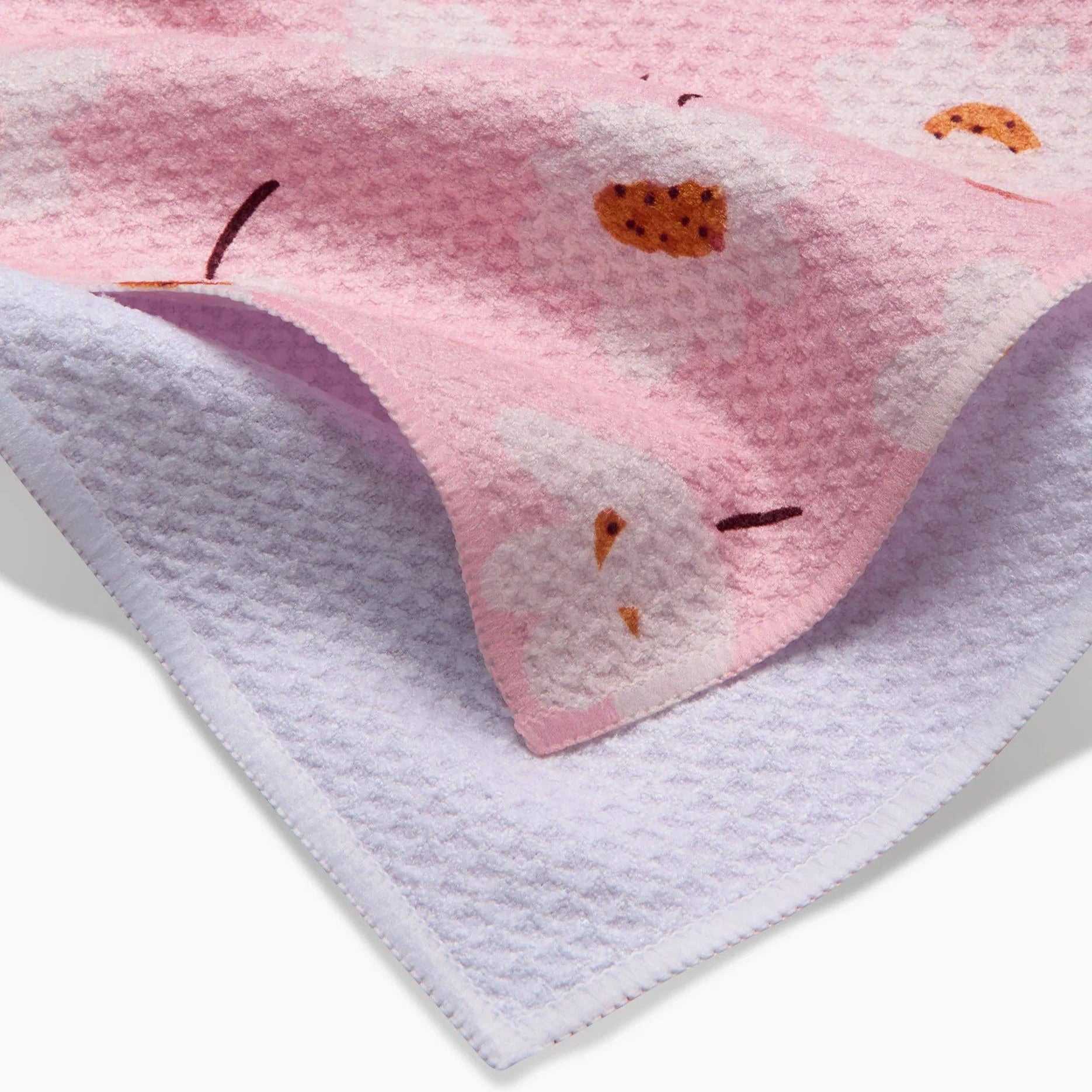 Pink and white textured fabric with small orange and black floral designs on a white background