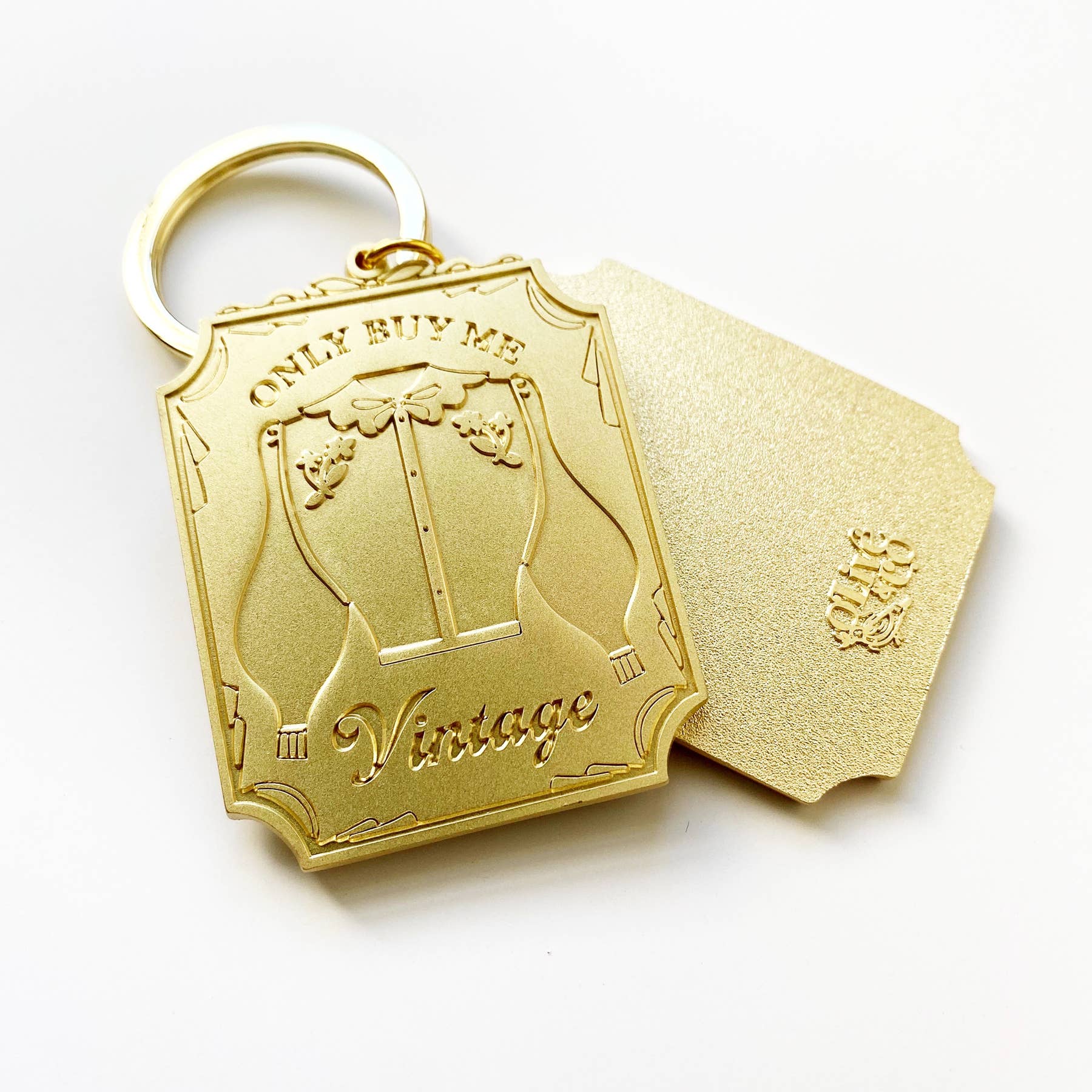 Carry your commitment to sustainable style with this brushed brass keychain. Featuring the bold "ONLY BUY ME VINTAGE" message on one side and the Olive &amp; Co logo on the reverse, it's a daily reminder to shop consciously. Perfect for vintage enthusiasts who want to celebrate their values while keeping keys organized in style.