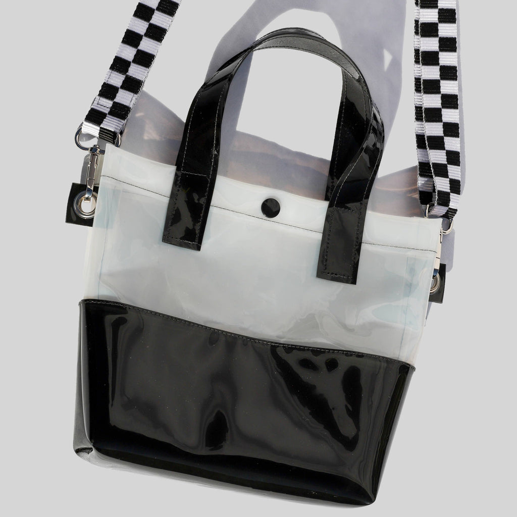Miss your jelly sandals? This is your new favorite bag! Keep everything inside with a snap. The black and white translucent vinyl handle bag has a black snap closure and is detailed with silver metal grommets. It's available with or without the detachable black and white checkered 1" strap