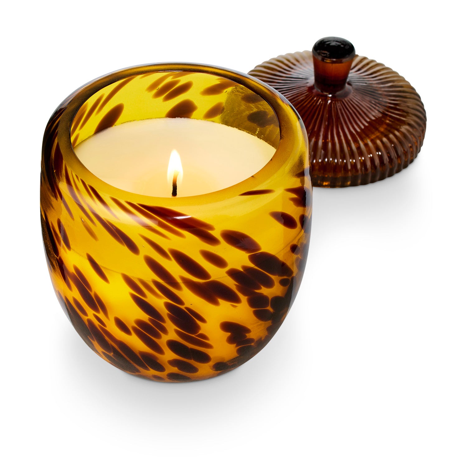 Candle in a tortoiseshell-patterned glass holder on a white background