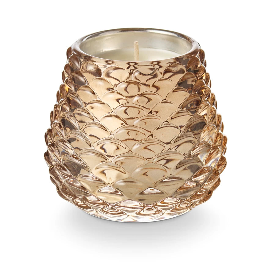 Decorative candle in a textured glass holder on a white background