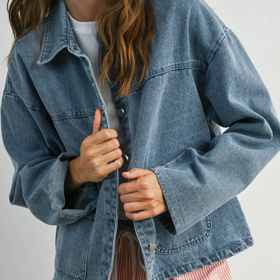 Medium wash denim jacket with silver buttons, box pockets, and collar. 