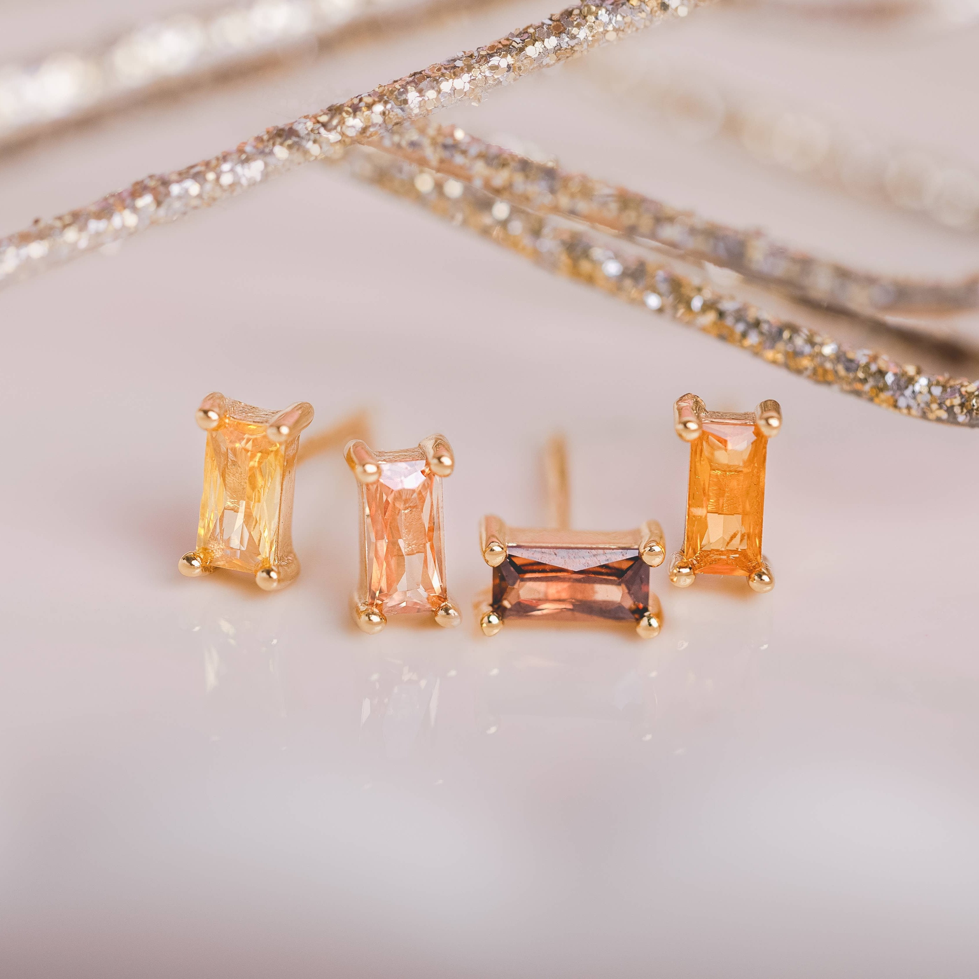  Birthstone Ombre Baguette Stud Earring Set, a collection of four stunning earrings crafted in 18k gold plated with an anti-tarnish coating. This set of stud earrings showcases the ombre effect, seamlessly blending hues from light to dark, creating a captivating visual representation of your birthstone's color spectrum. 