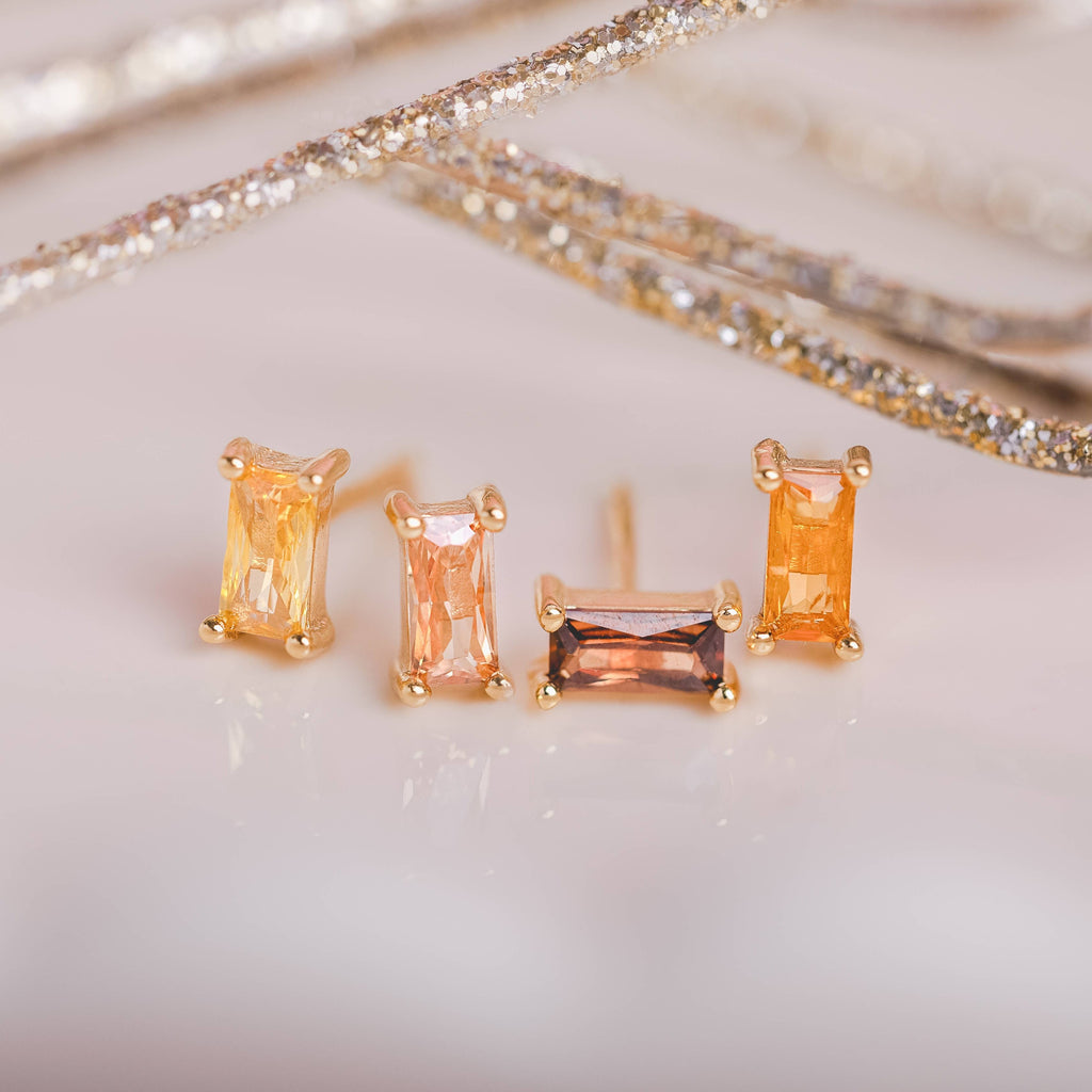  Birthstone Ombre Baguette Stud Earring Set, a collection of four stunning earrings crafted in 18k gold plated with an anti-tarnish coating. This set of stud earrings showcases the ombre effect, seamlessly blending hues from light to dark, creating a captivating visual representation of your birthstone's color spectrum. 