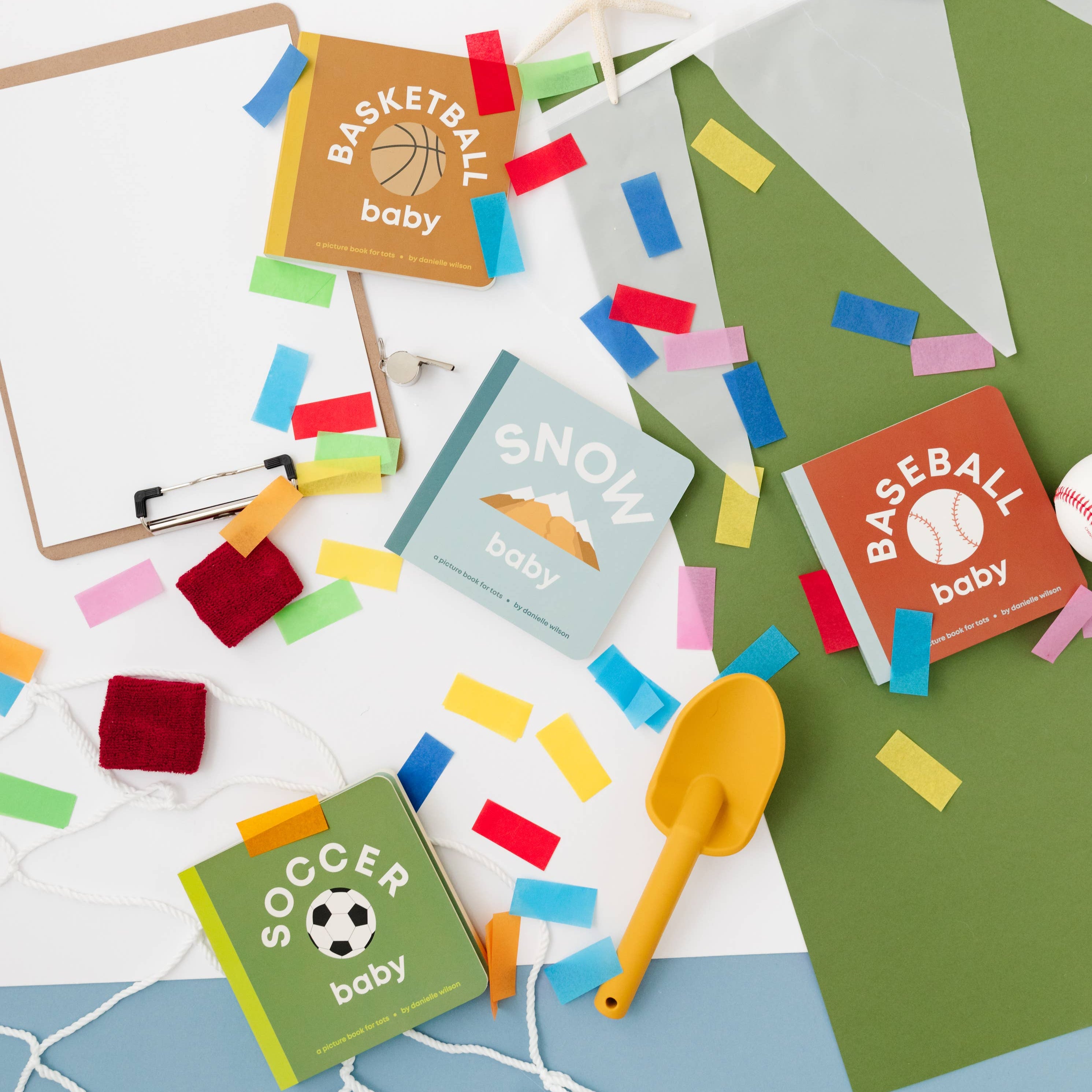 Colorful baby shower decorations with books and confetti on a white surface