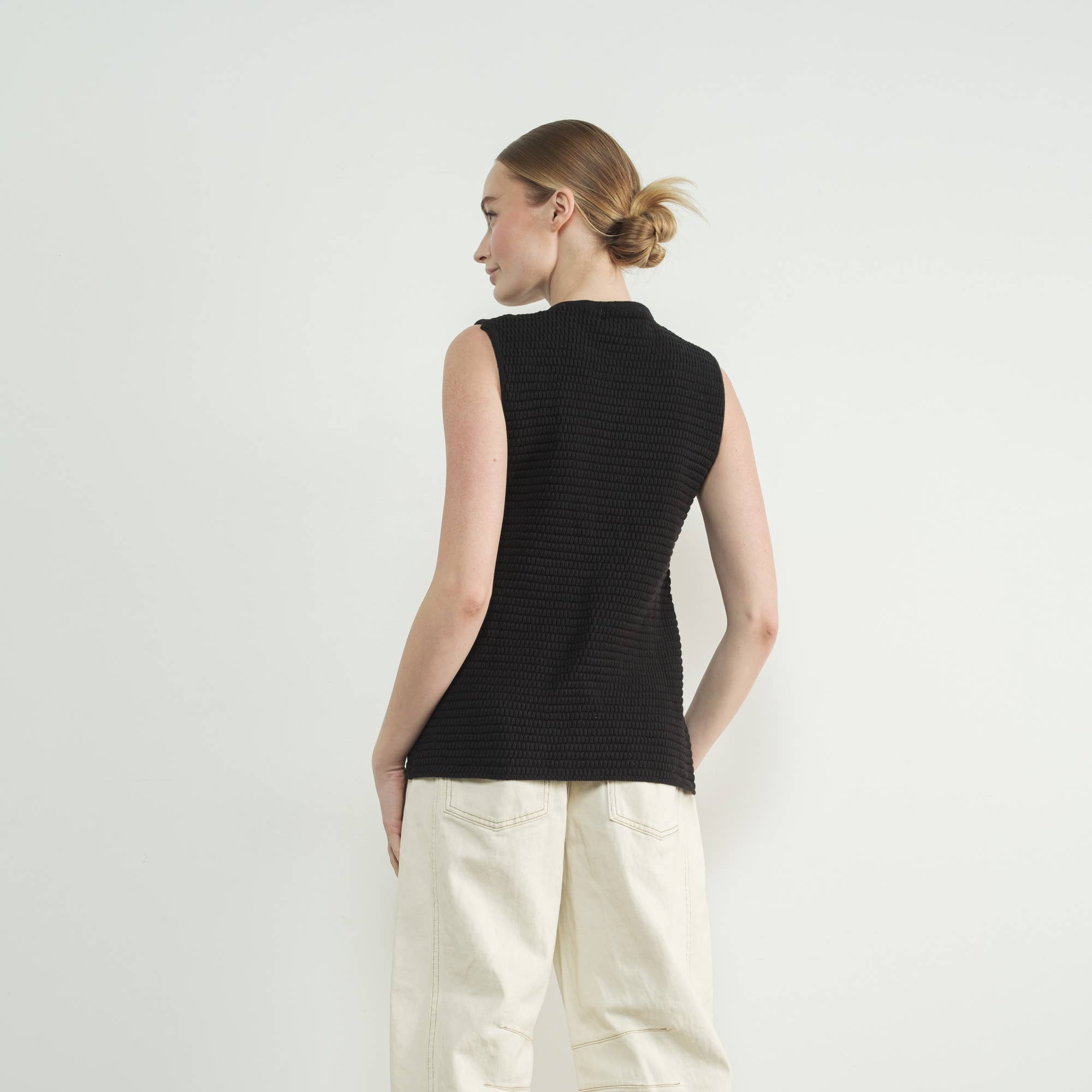 This black sweater vest is the epitome of cozy-chic style, featuring allover ribbed texture and classic button-up closure for a refined yet modern aesthetic. Designed for versatility, it can be worn as a standalone statement. Fitted silhouette that beautifully enhances femininity and complements any outfit.&nbsp;