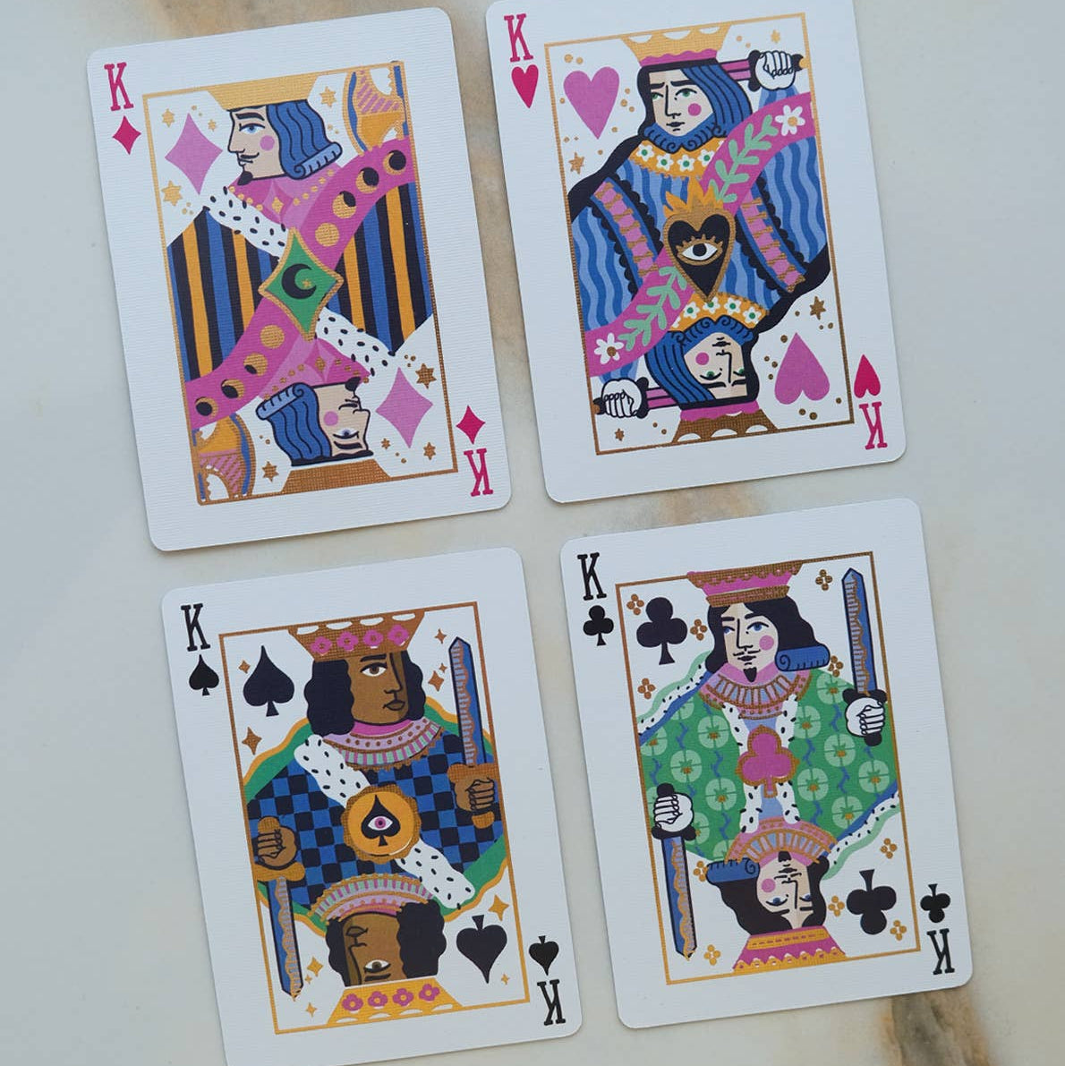 Four playing cards with colorful designs on a light background