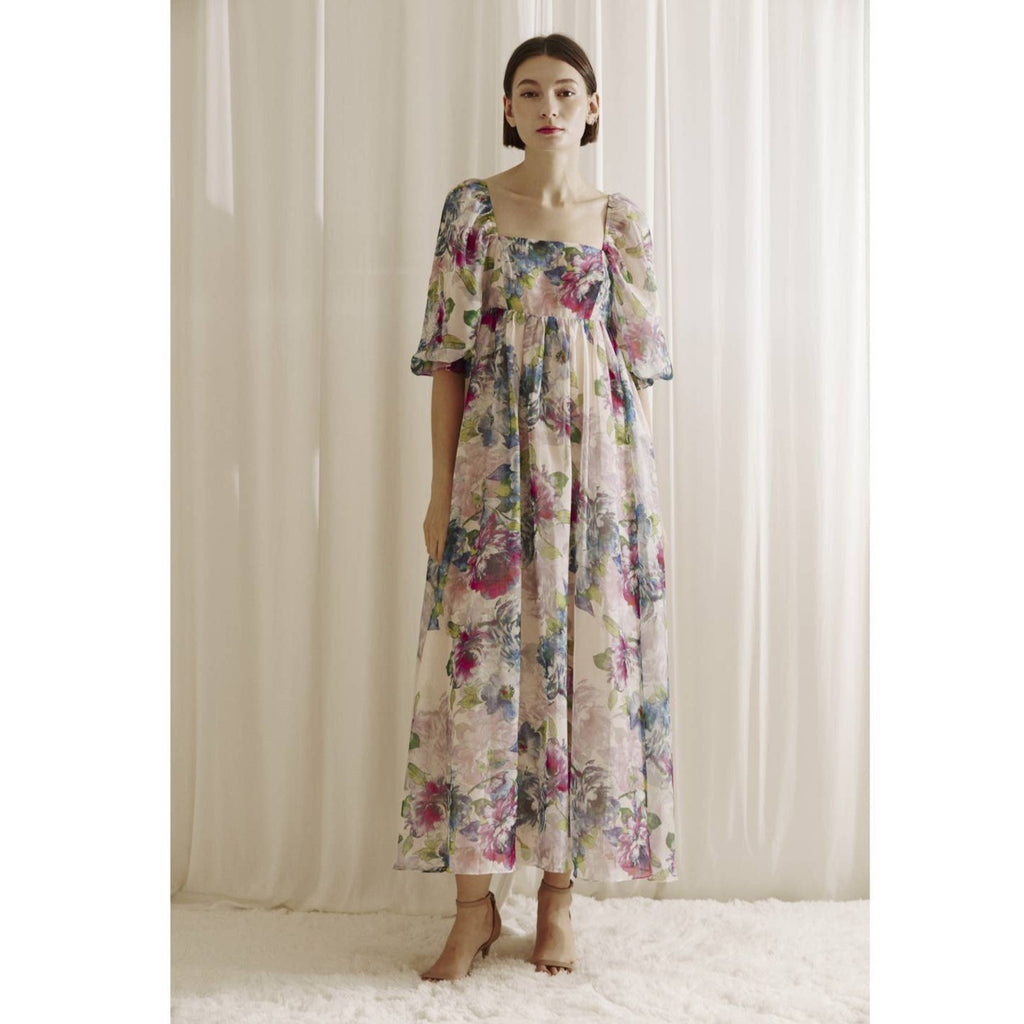 Multi-color watercolor floral print maxi baby doll dress. It shows a square neckline, 3/4 puffy sleeves, and bust darts. It also has an empire, gathered waist, back zipper, and flowy bottom.