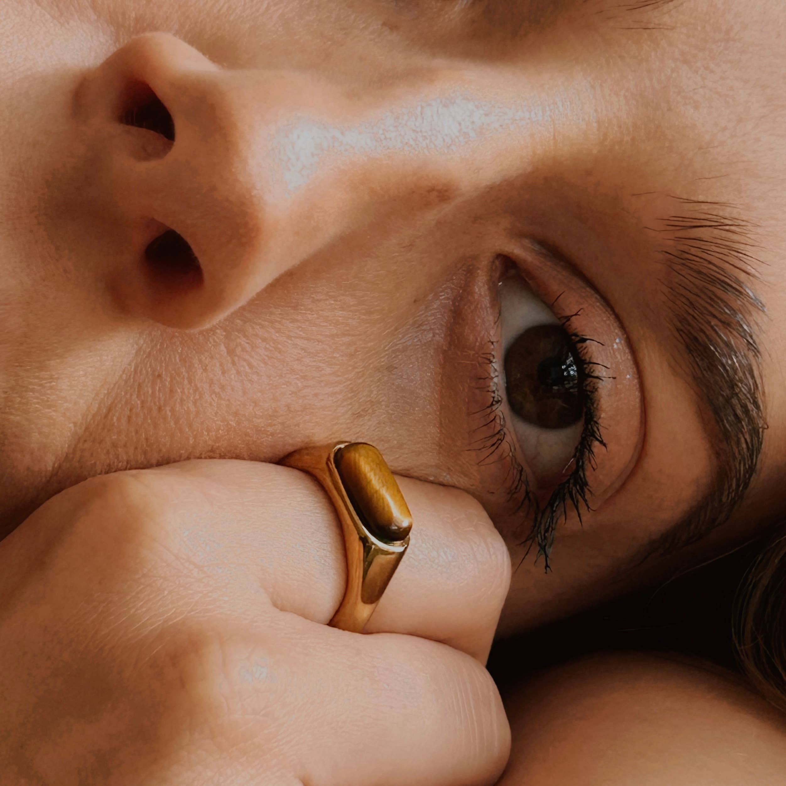 Close-up of a person wearing a gold ring on their finger.