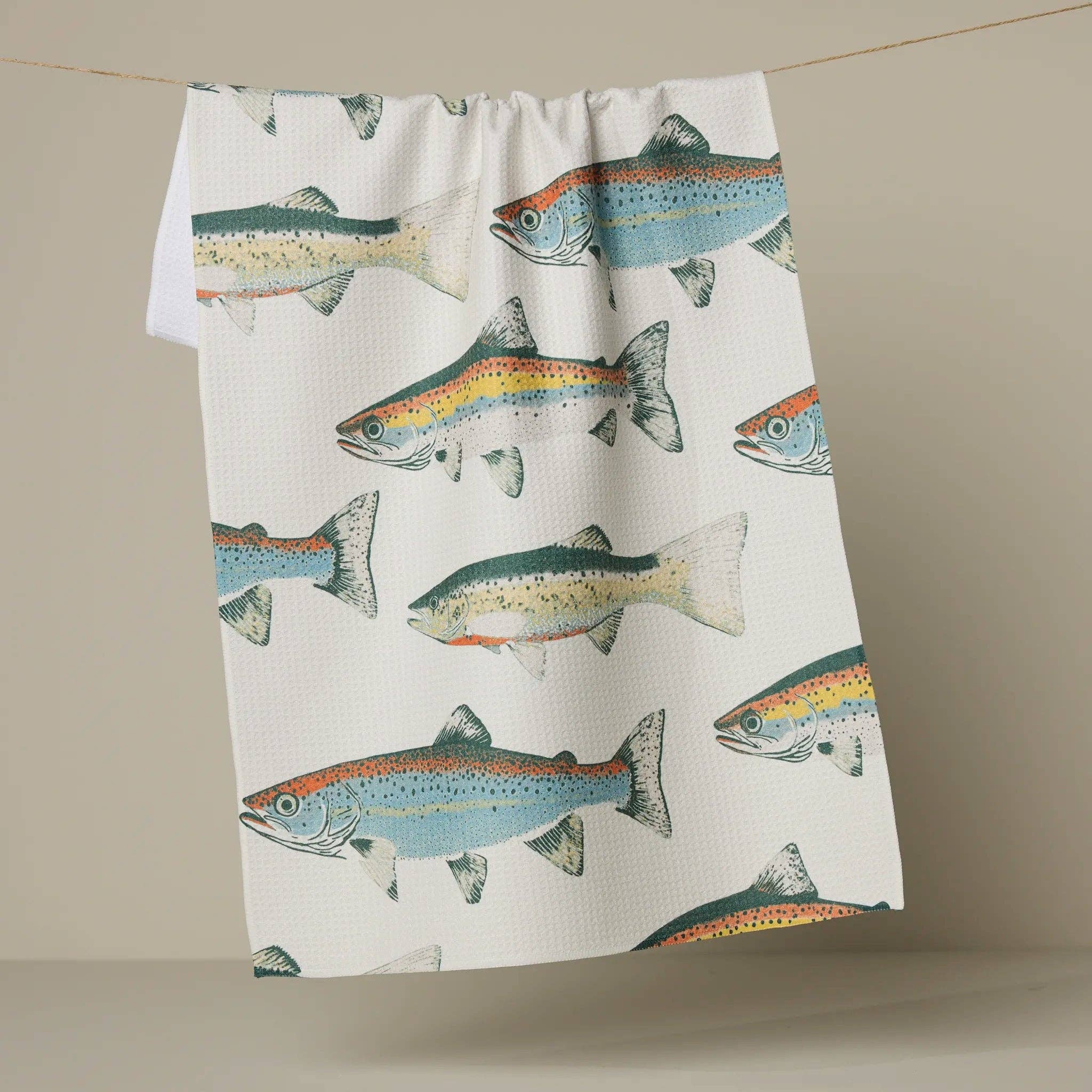 Tea towel with fish pattern hanging on a line against a beige background