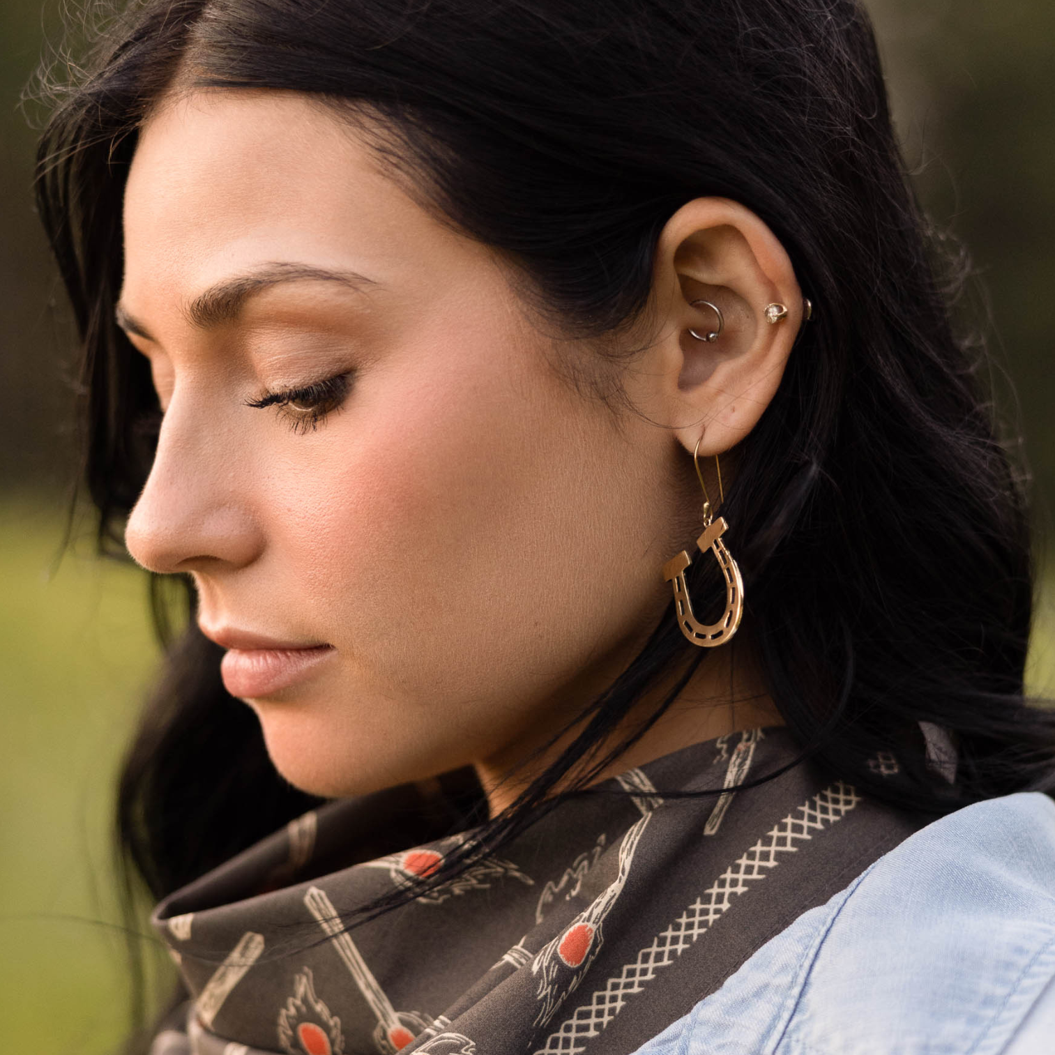 Close-up of a woman wearing hoop earrings with a blurred natural background