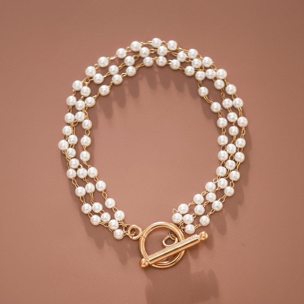 Elevate your everyday style with this sophisticated 18K gold plated stainless steel bracelet featuring delicate multi-string pearl detailing. Crafted for durability, it's hypoallergenic, waterproof, and sweatproof—perfect for layering or wearing solo. The tarnish-resistant finish maintains its lustrous shine, though we recommend avoiding prolonged contact with lotions, perfumes, and harsh chemicals to preserve the gold plating's brilliance. A timeless piece that transitions seamlessly from day to night.