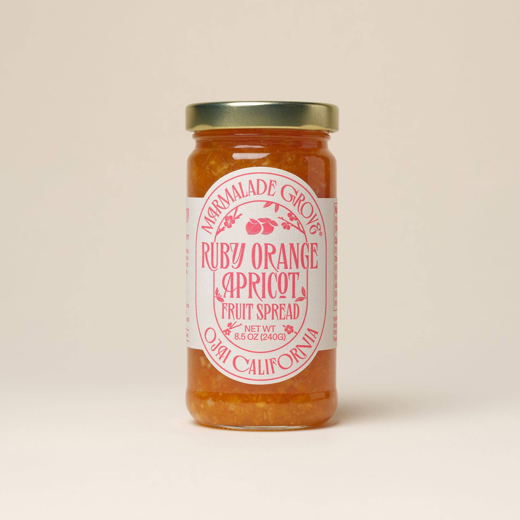 Jar of Ruby Orange Capricot fruit spread with a label on a beige background