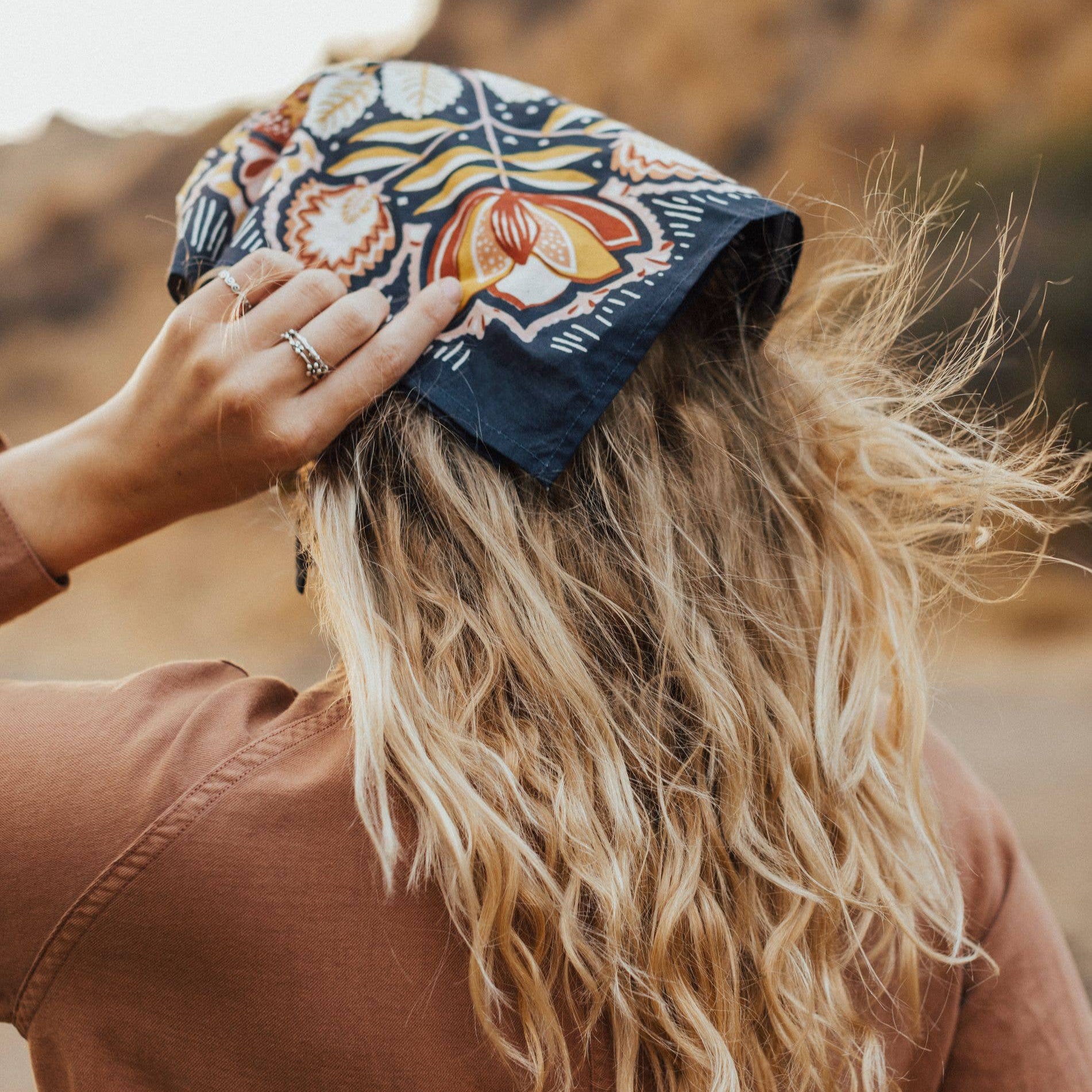 Person wearing a colorful headscarf with a blurred natural background
