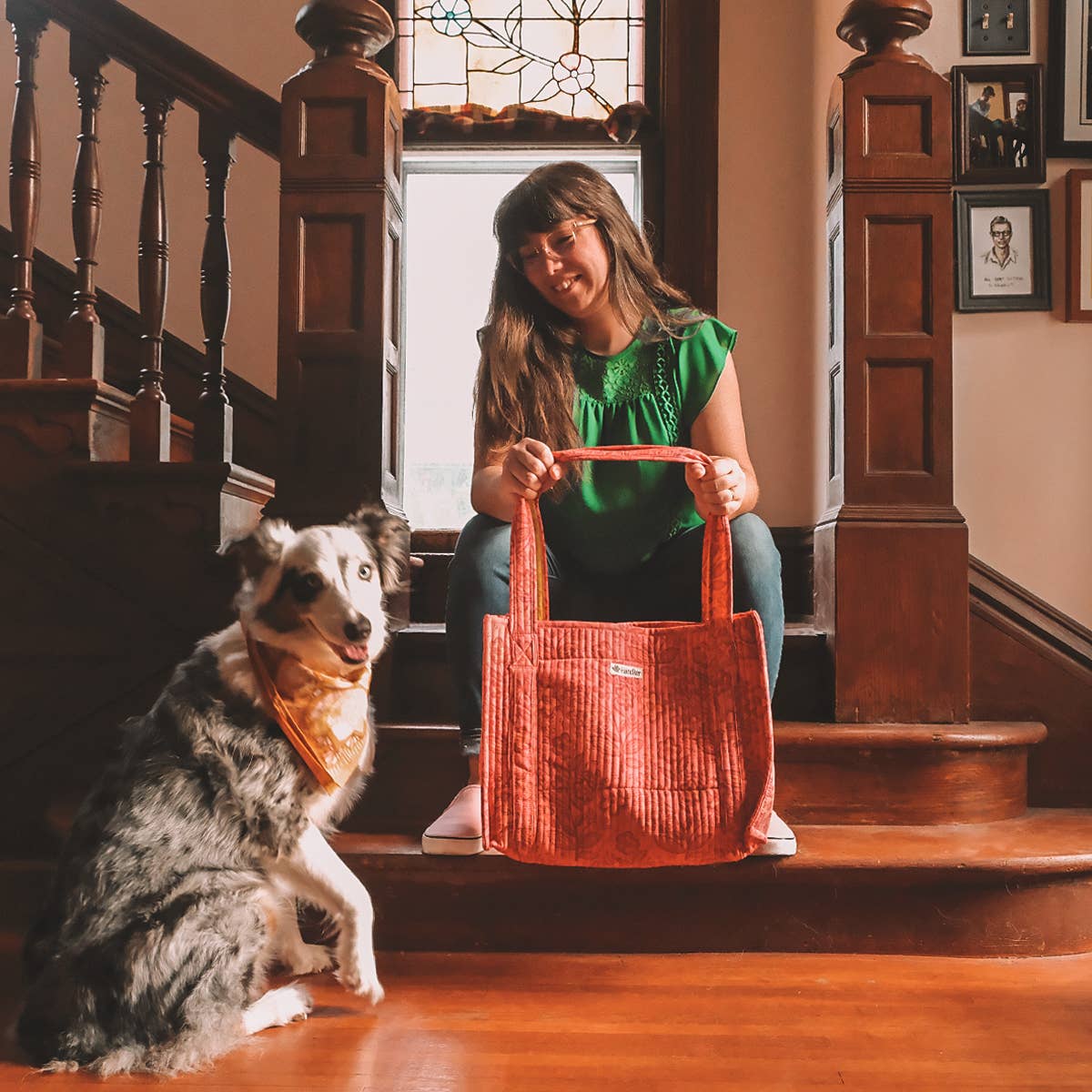 Woman holding a red bag with a dog sitting on the floor in a home setting.