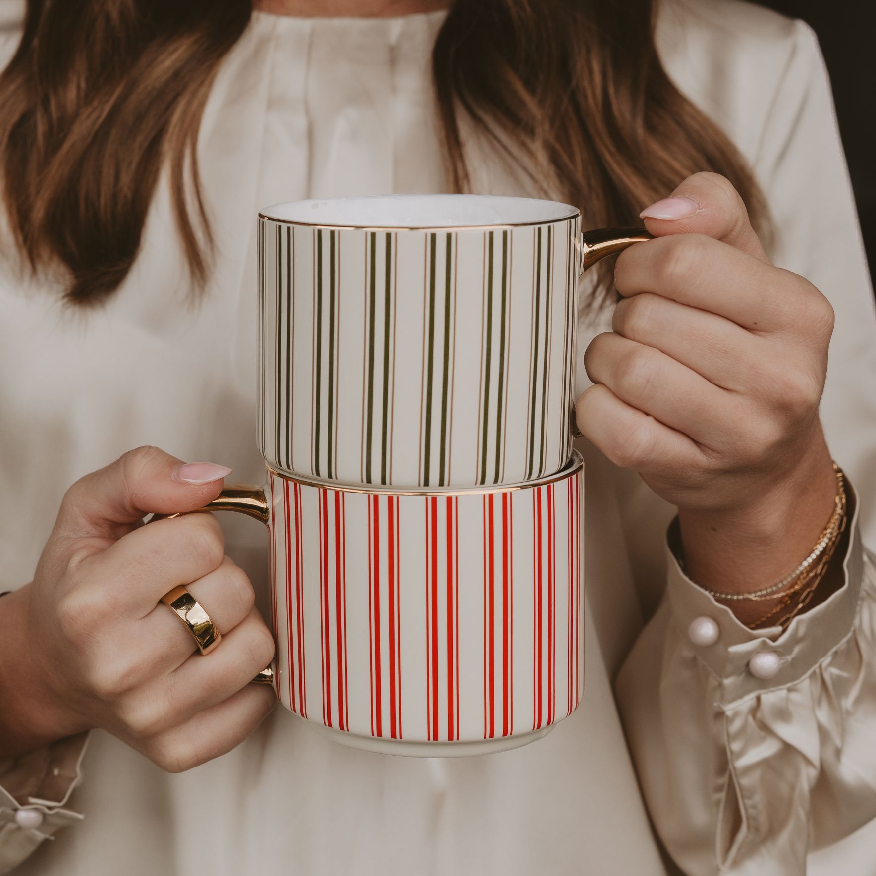 Person holding a striped mug with red, white, and black patterns.