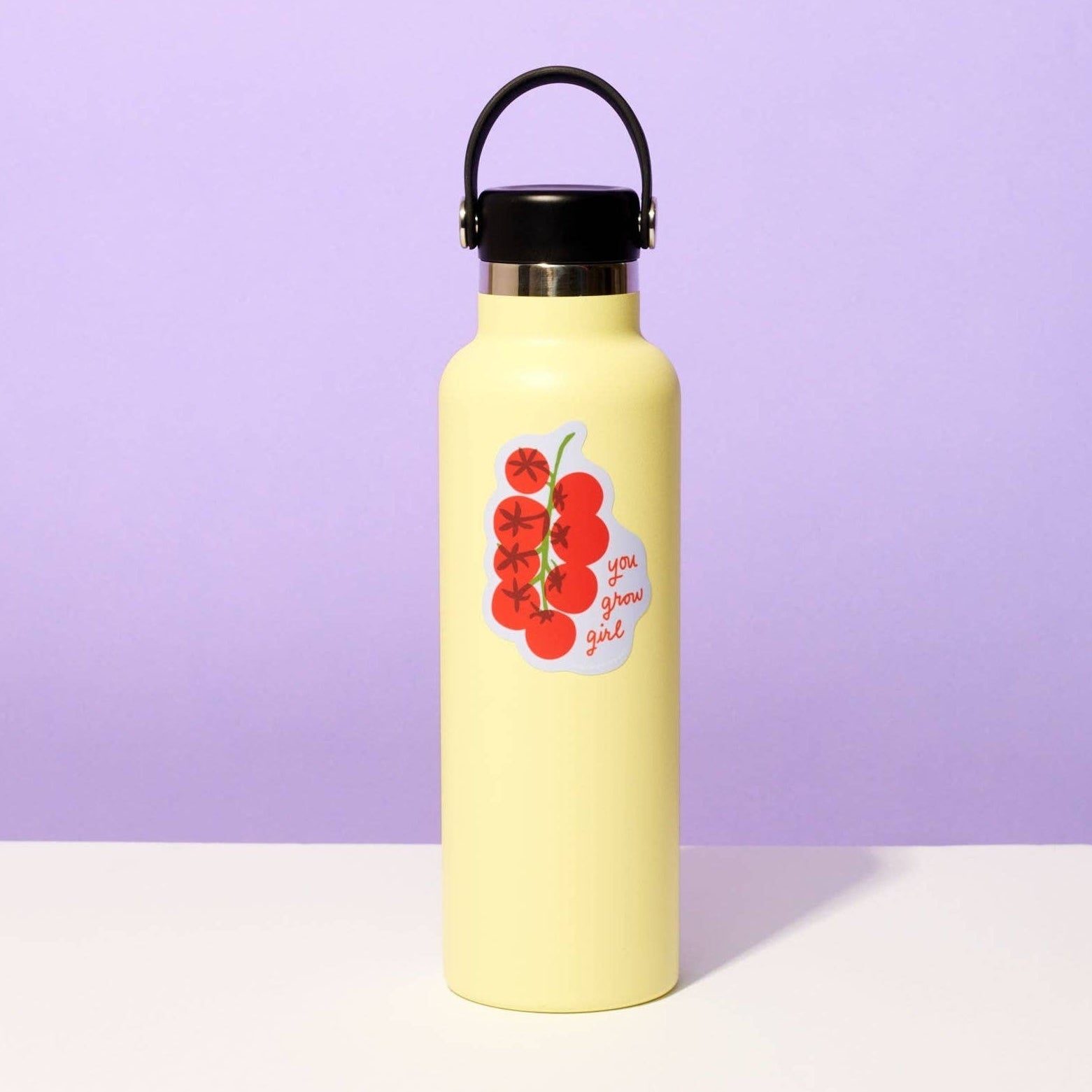 Yellow water bottle with red berry design on a purple background