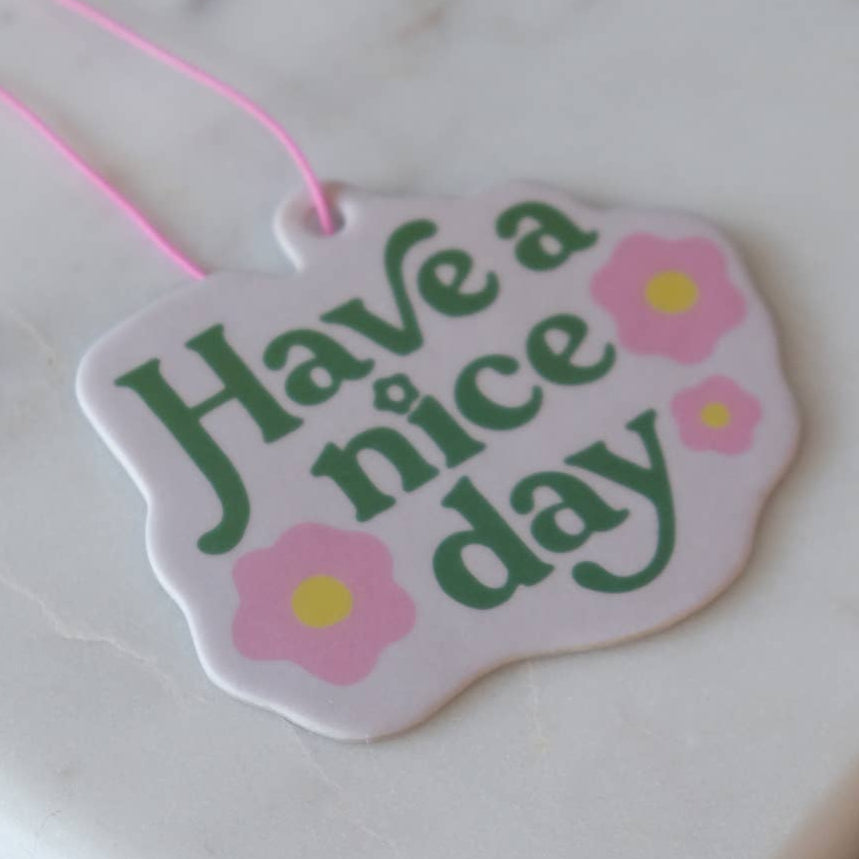 Decorative air freshener with 'Have a nice day' text and flowers on a white background