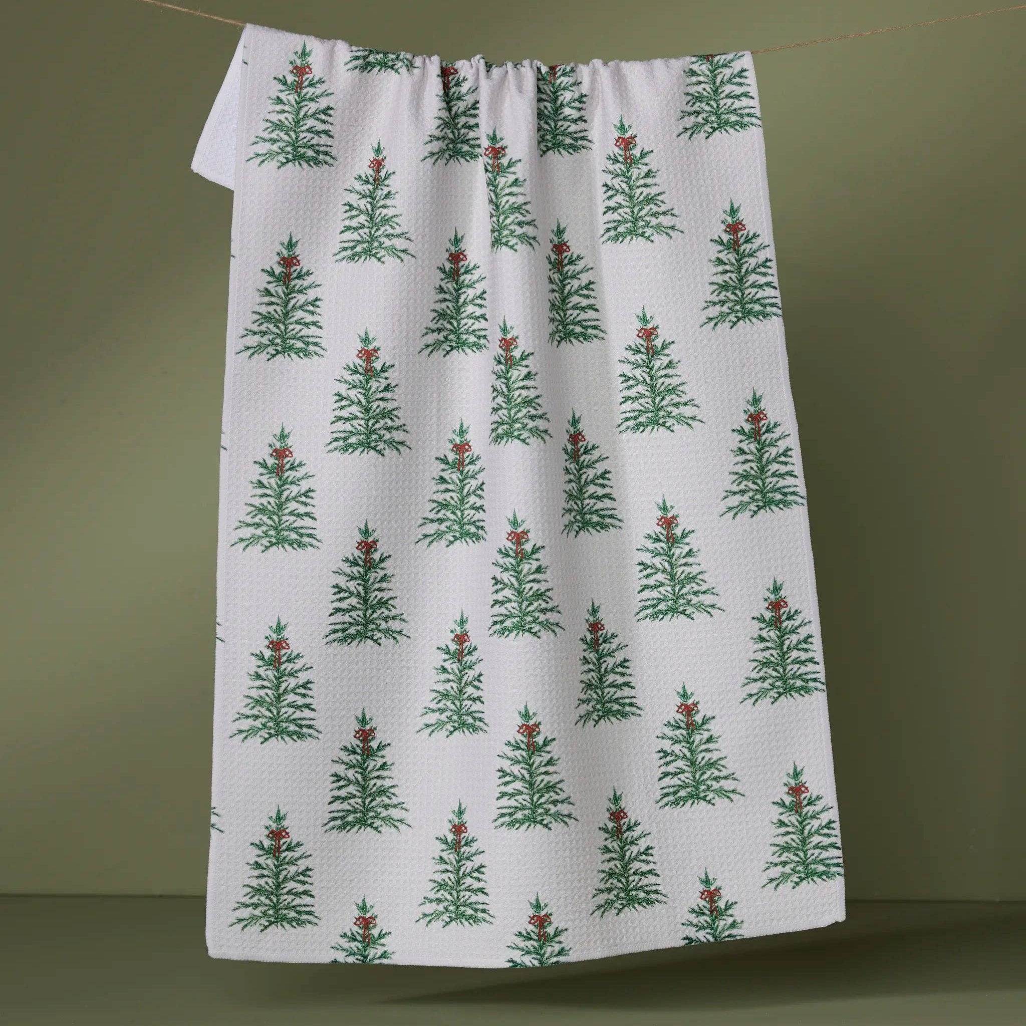 White towel with green tree pattern hanging on a line against a green background